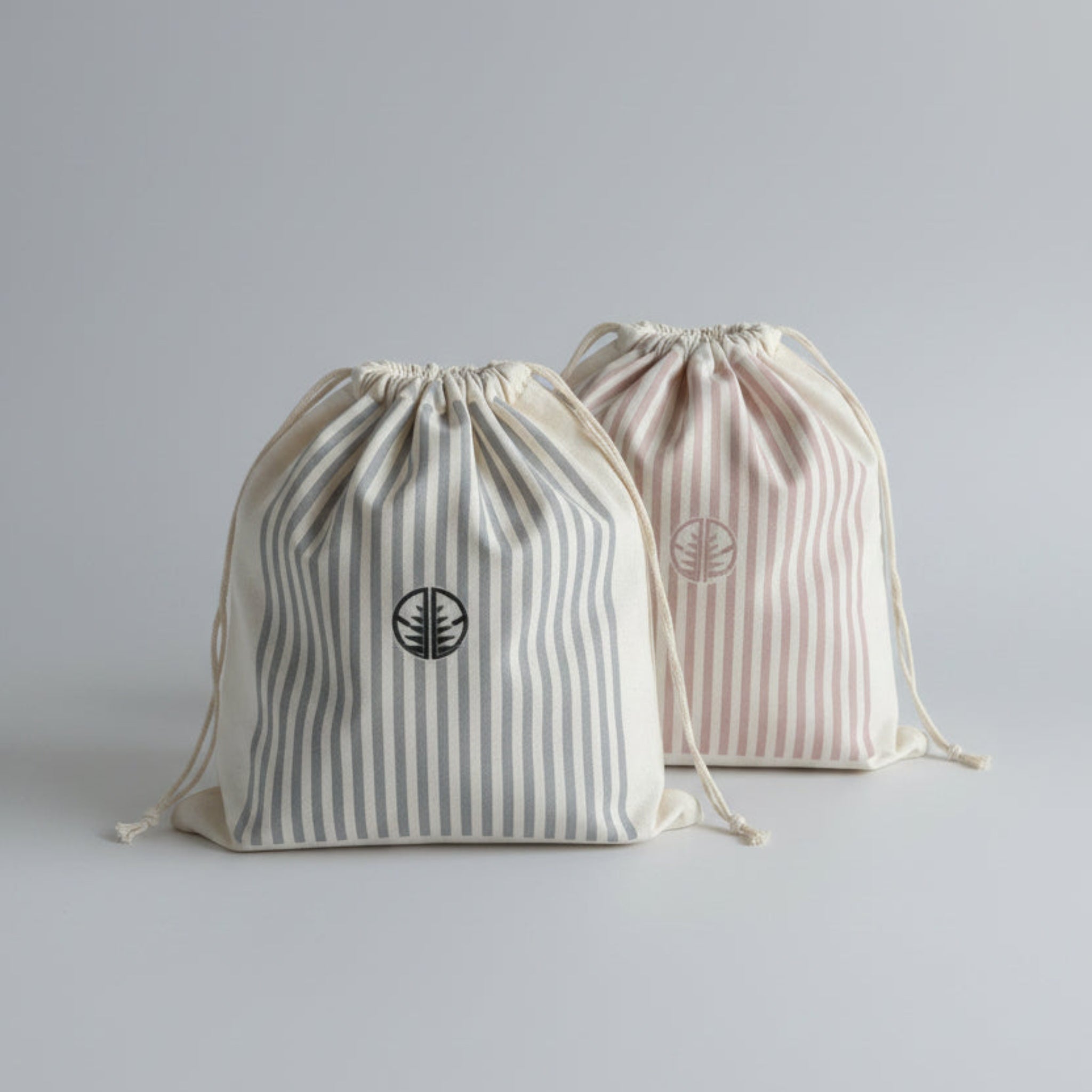 Two striped gift bags with 'AG' logo in pink stripes and blue stripes.