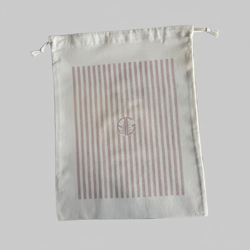 Natural cotton drawstring pouch with pink strips and 'AG' logo.