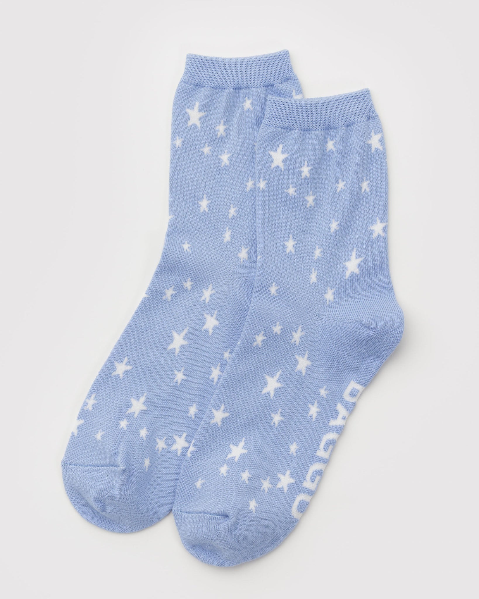 Pair of light blue socks with white star patterns and BAGGU woven on sole.