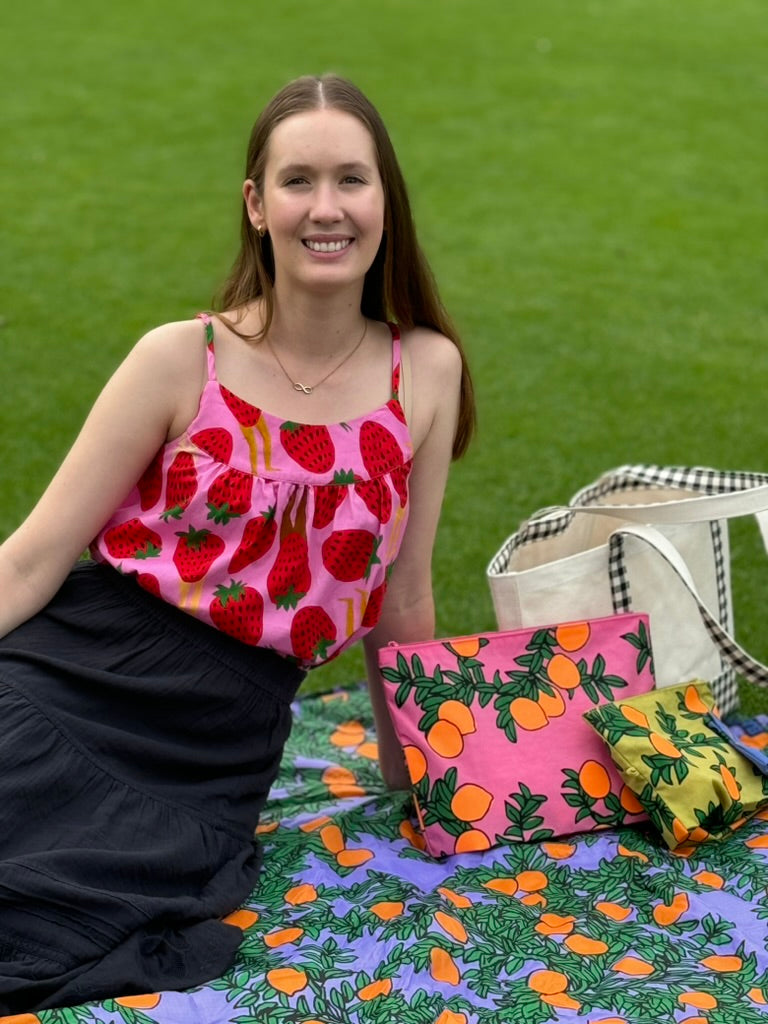women-wearing-cami-top-pink-sweet-legs-sitting-on-picnic-rug-in-orange-tree-periwinkle