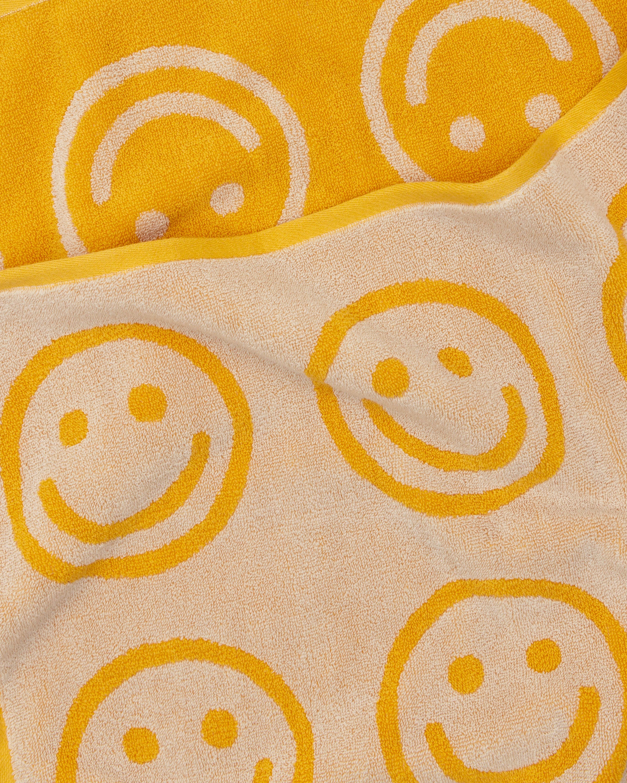 Pattern of smiley faces on a yellow towel.