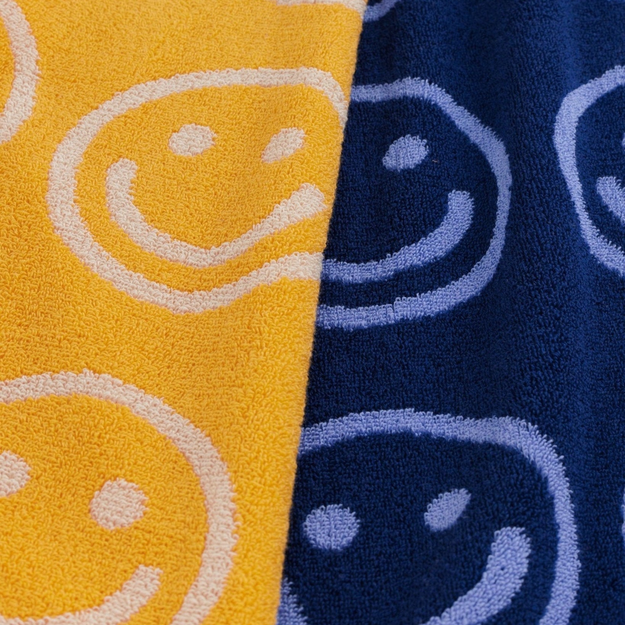 Baggu Reversible Hand Towel Set of 2 in a blue and a yellow colour each with a smiley face print.