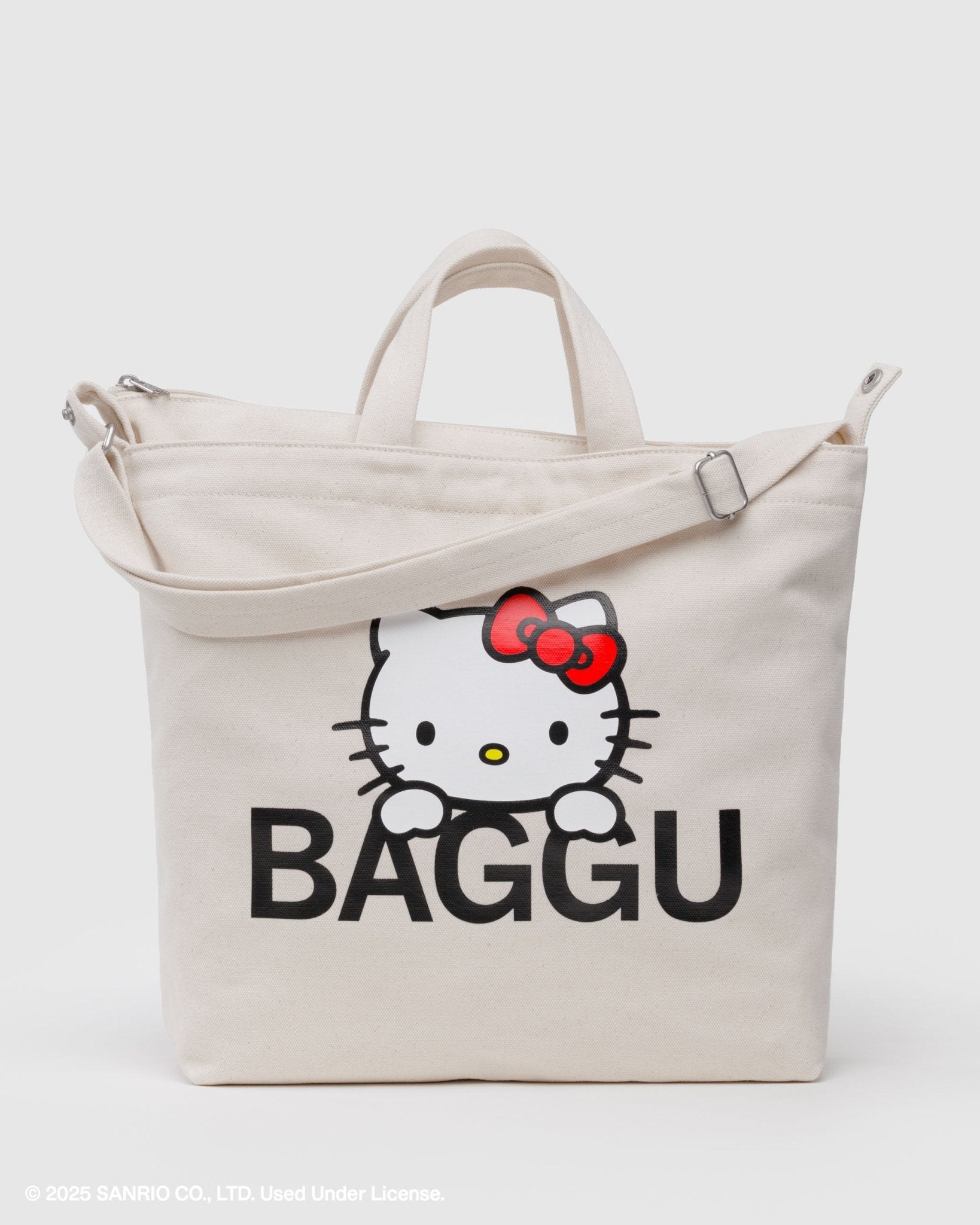 Ecru tote bag with long strap and short carry handles printed with with Hello Kitty photo design and black 'BAGGU' text on front.