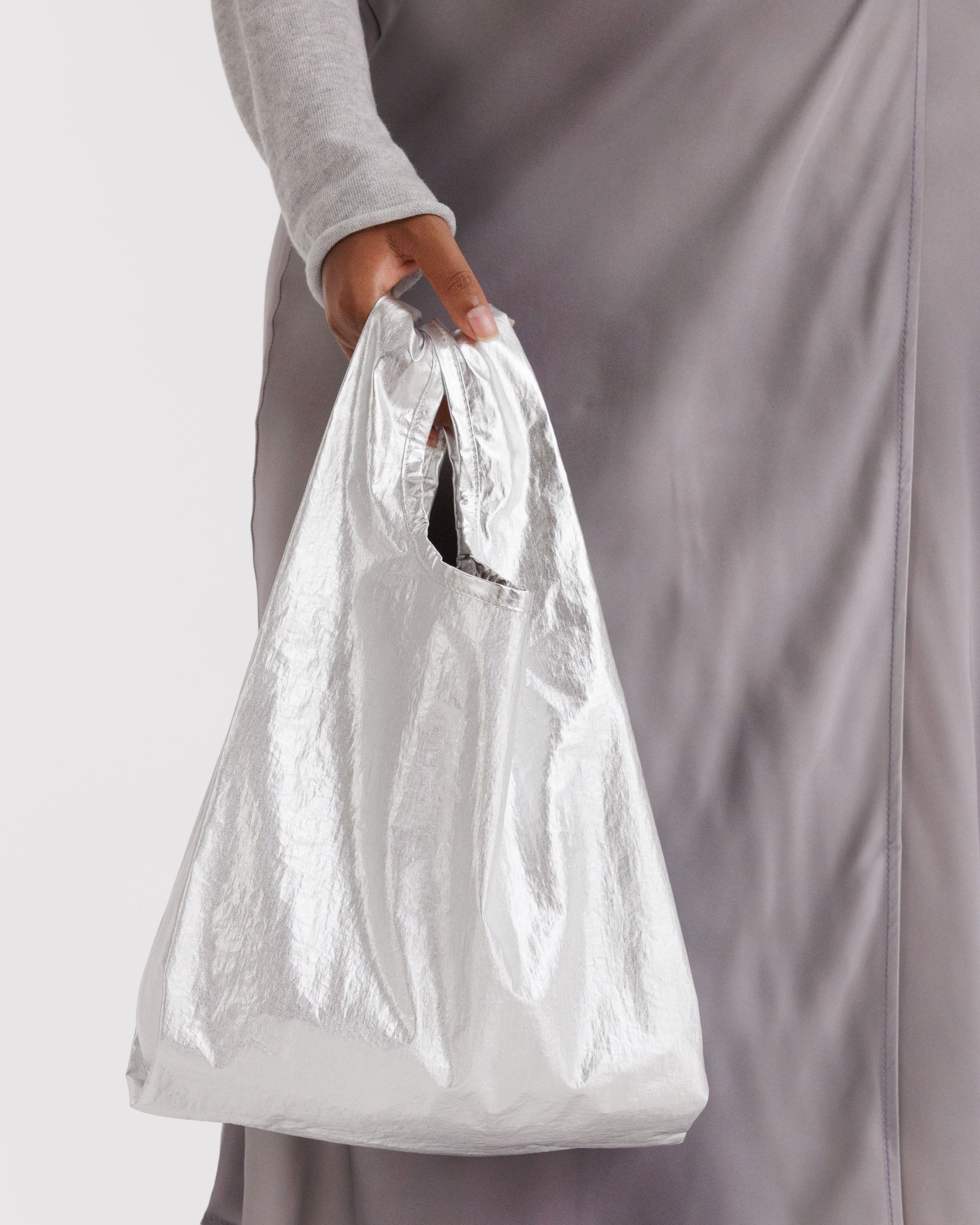 Person holding a small chrome metallic tote bag.