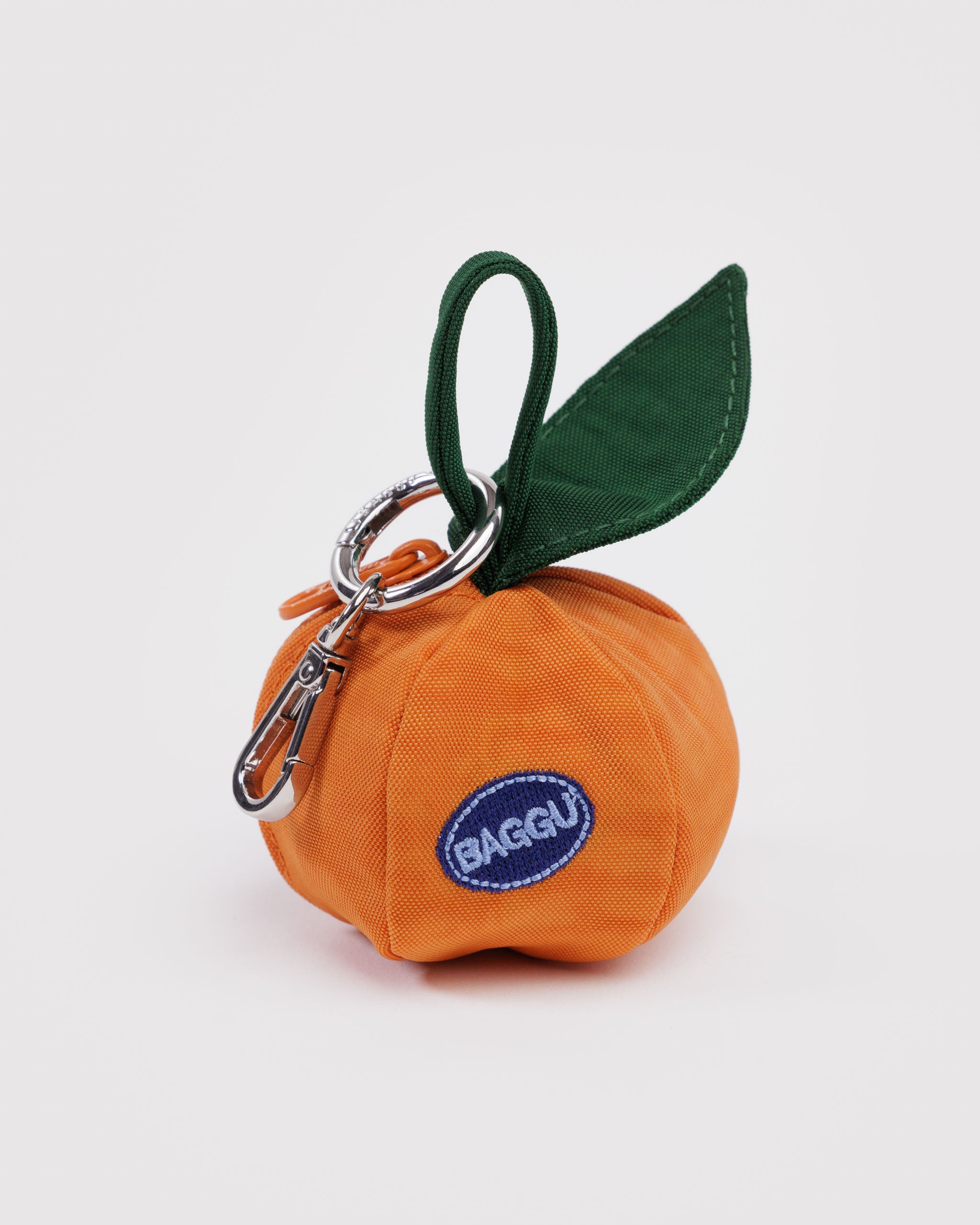 Orange fruit-shaped bag charm with keychain, a green leaf and 'BAGGU' logo.