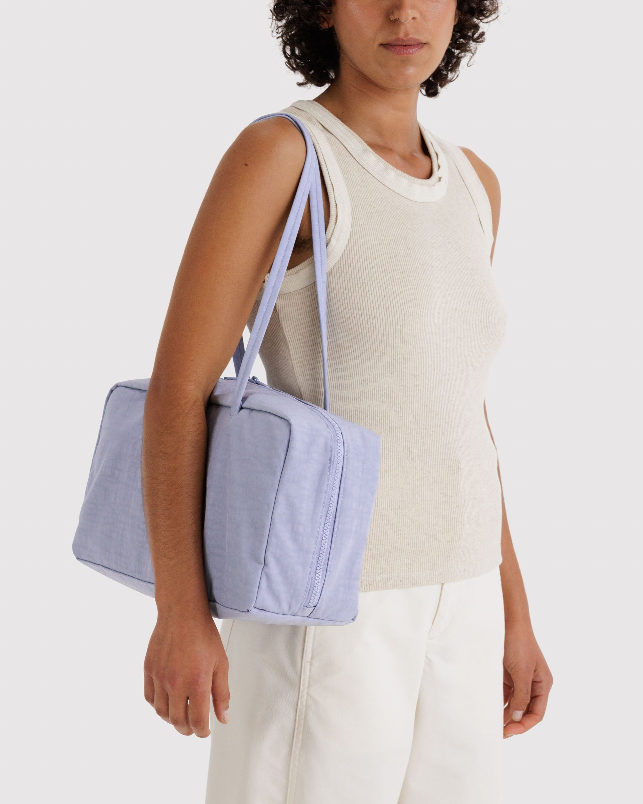 Woman holding a light blue handbag on shoulder.
