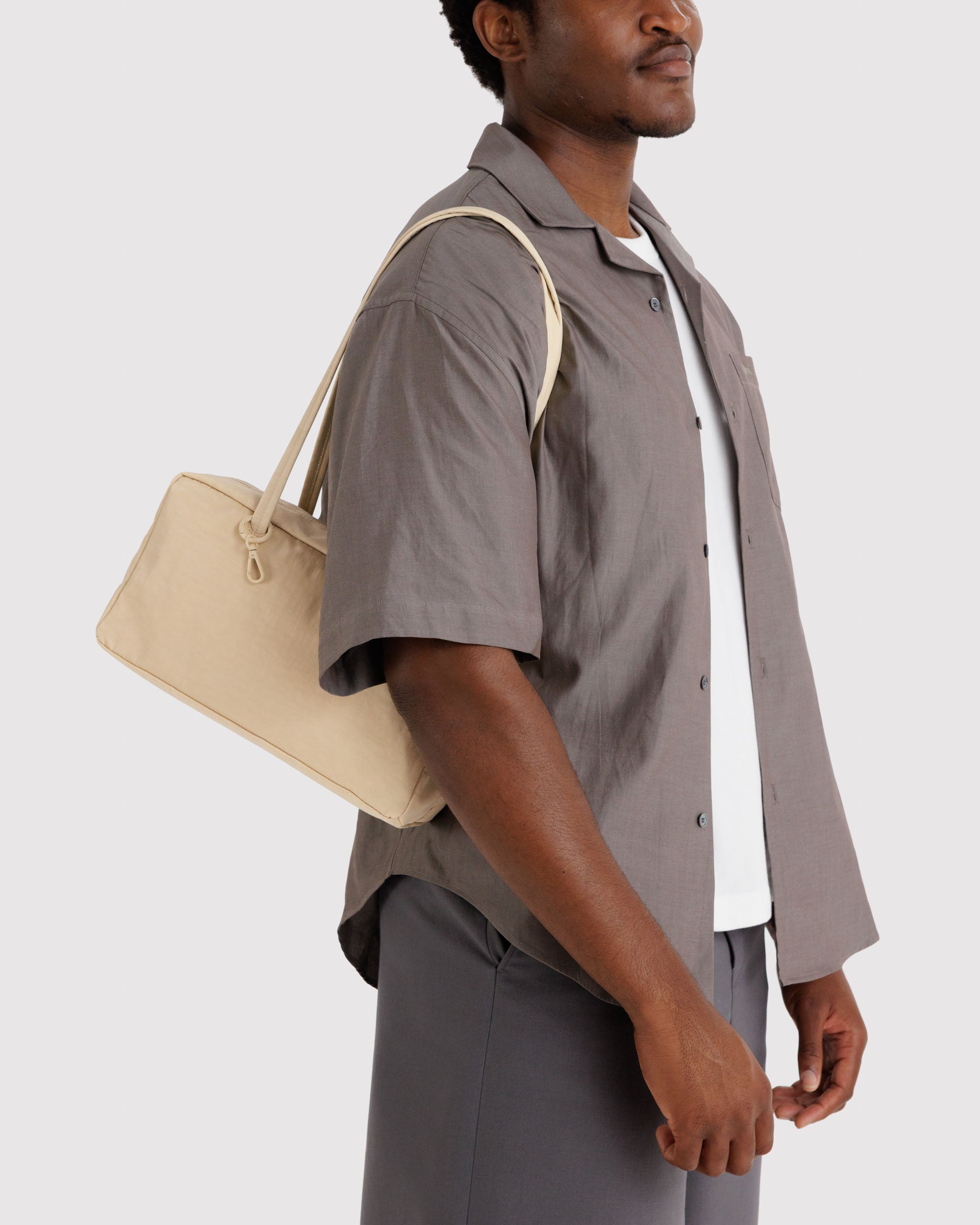 Man carrying a light yellow handbag on shoulders.