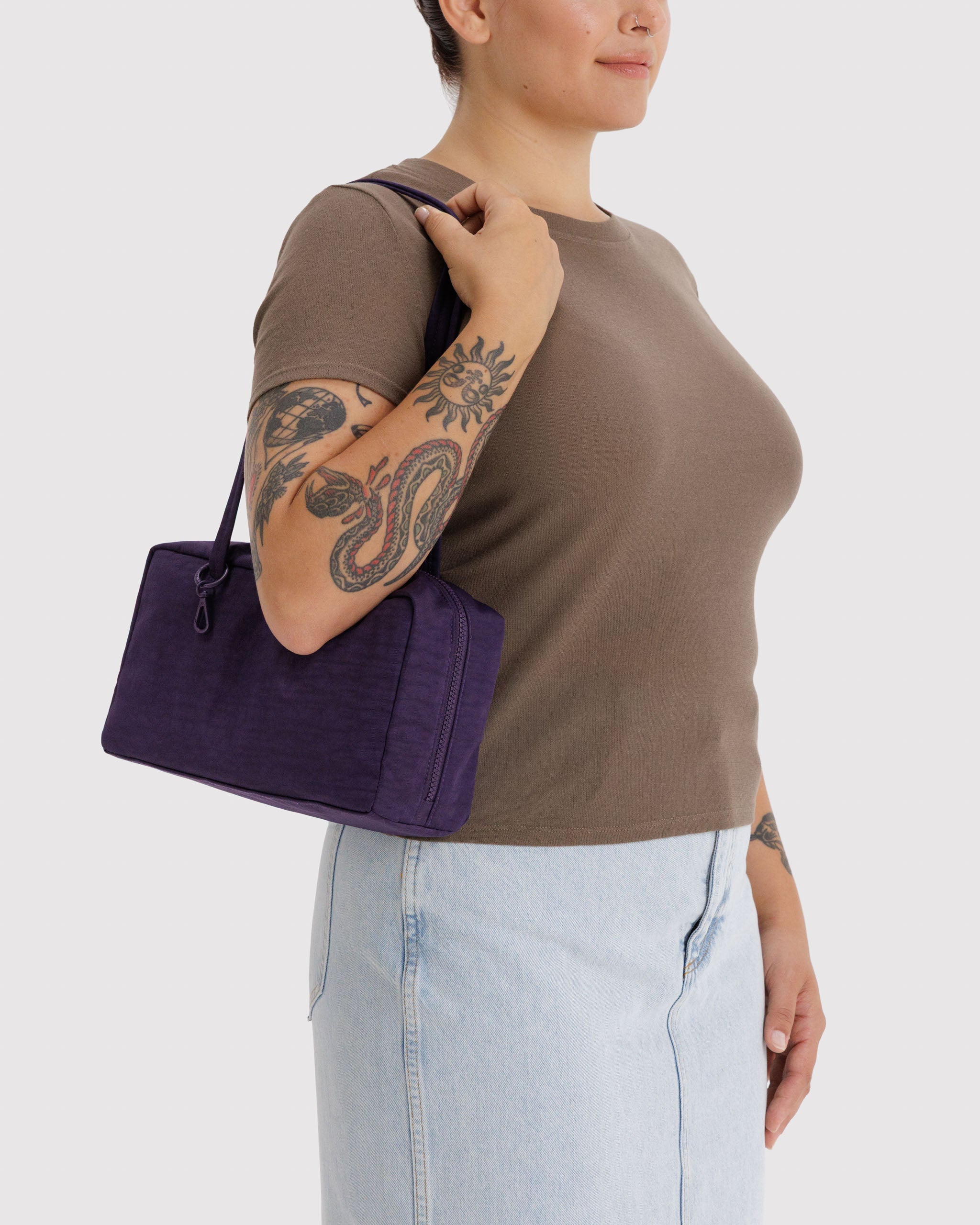 Woman holding a purple handbag on shoulders.