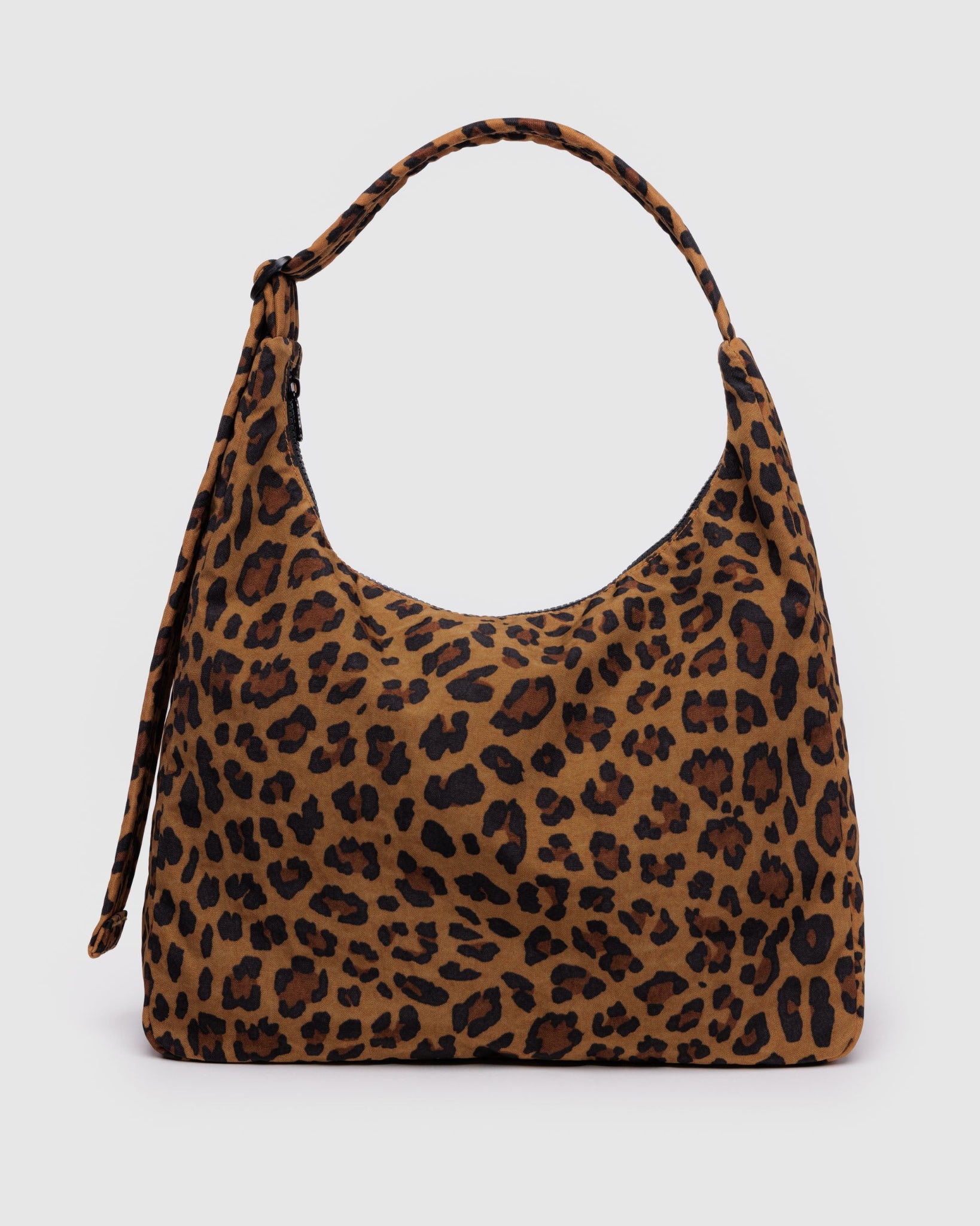 Leopard print handbag with adjustable shoulder strap and top zipper standing on its flat base.