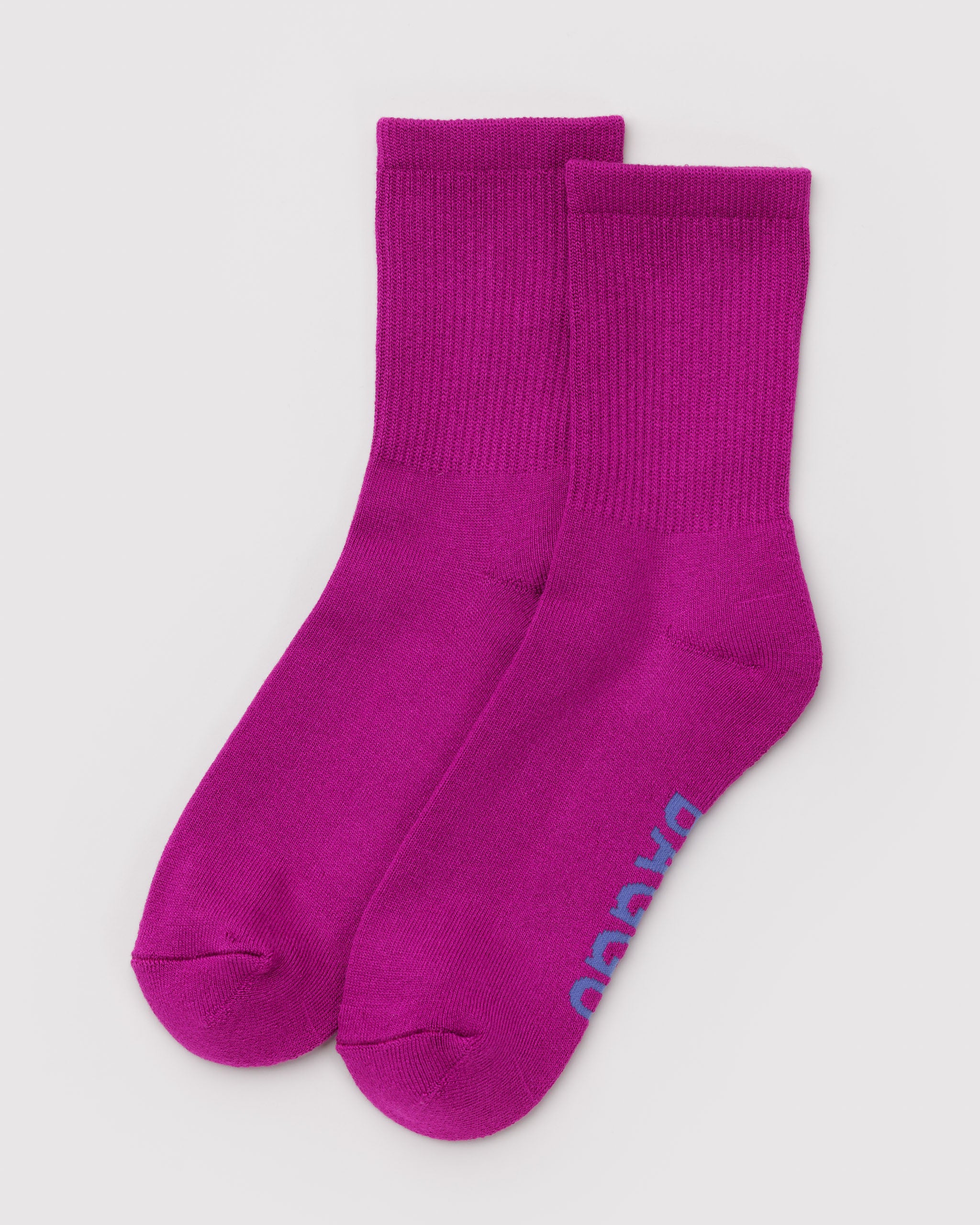 Pair of bright pink ribbed crew socks with a brand logo on sole.