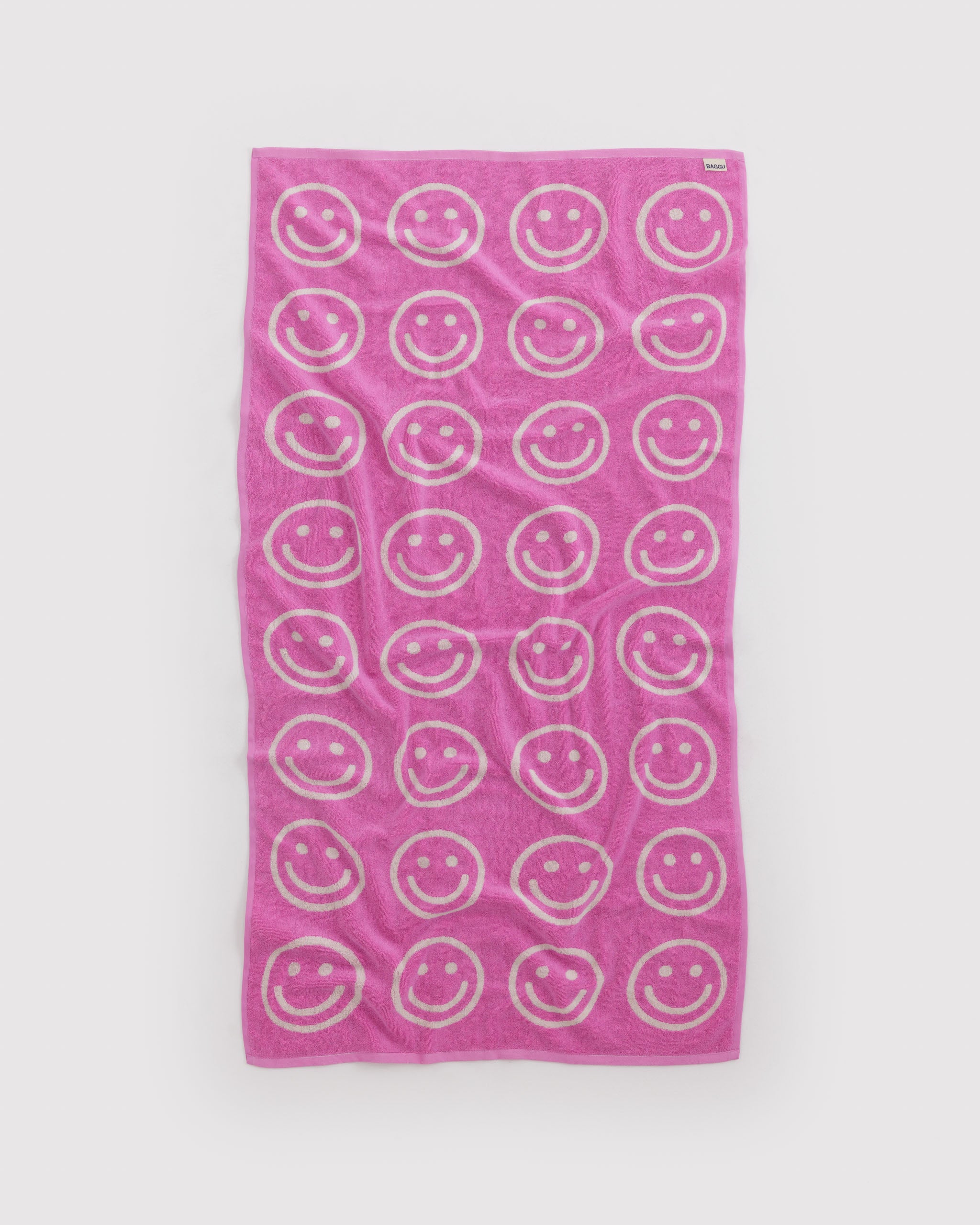 Reversible back side pink towel with white smiley face pattern.