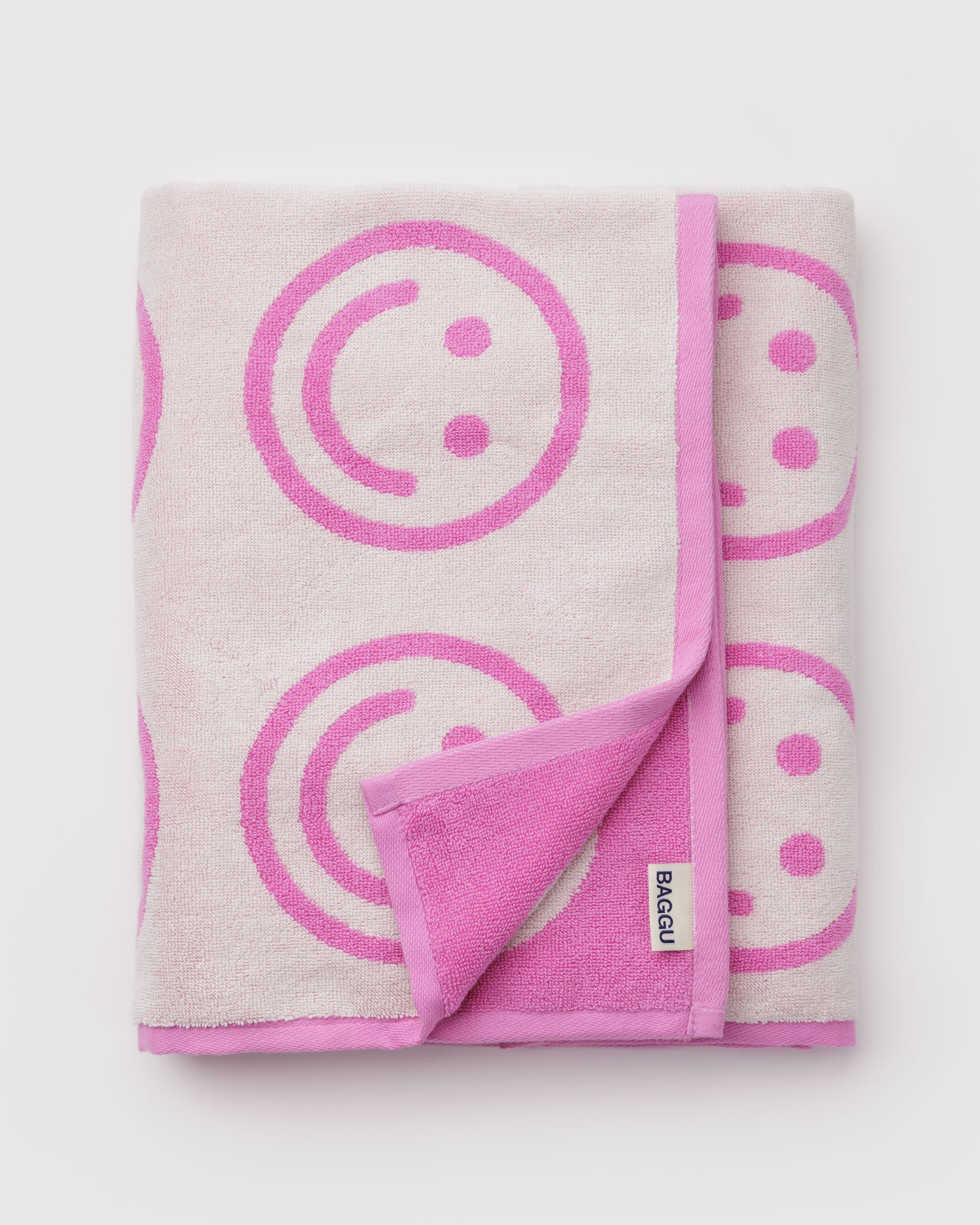 Folded towel with pink smiley face patterns on a light pink background