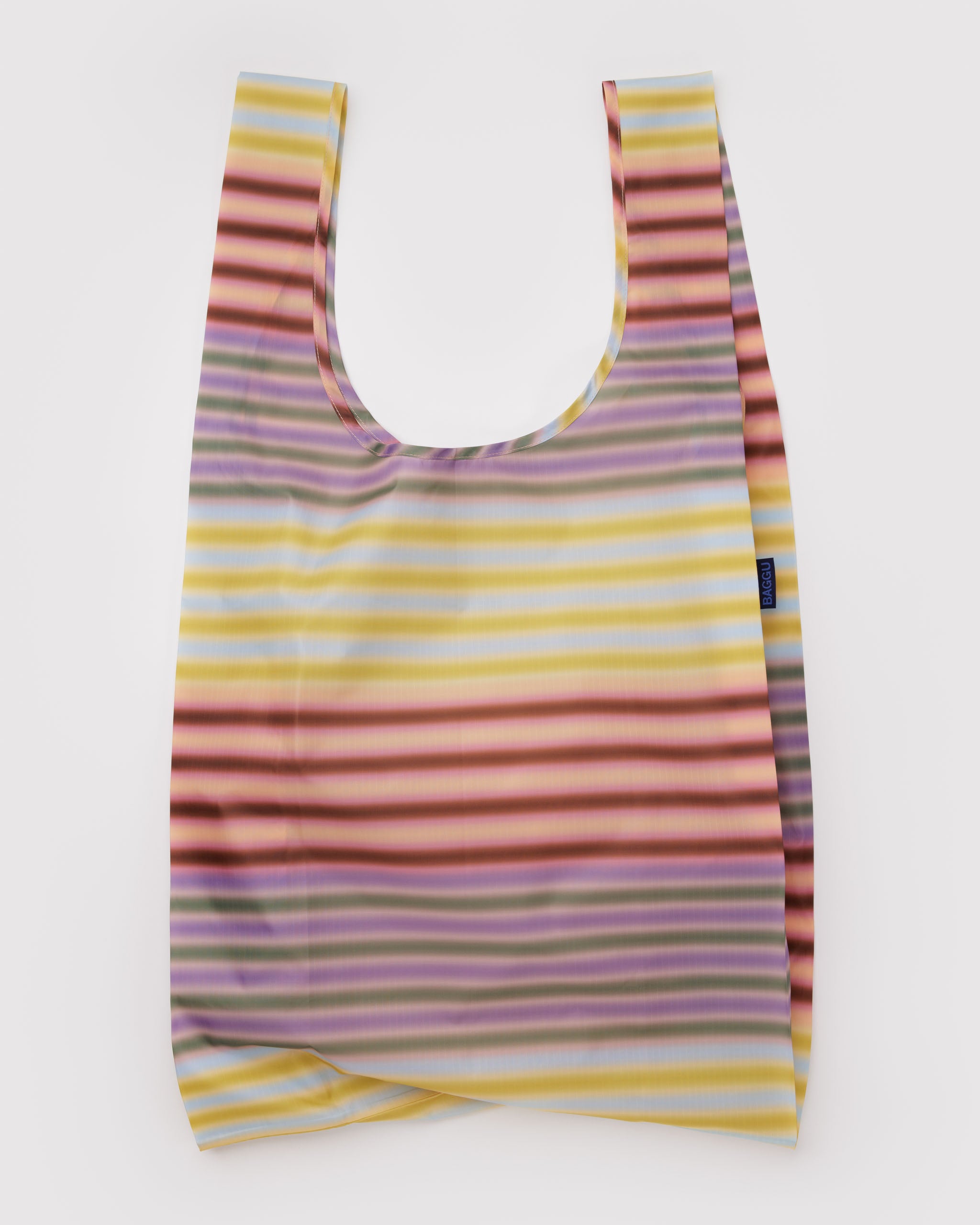 Orange, purple and yellow multicoloured striped reusable tote bag with BAGGU logo tag at side.