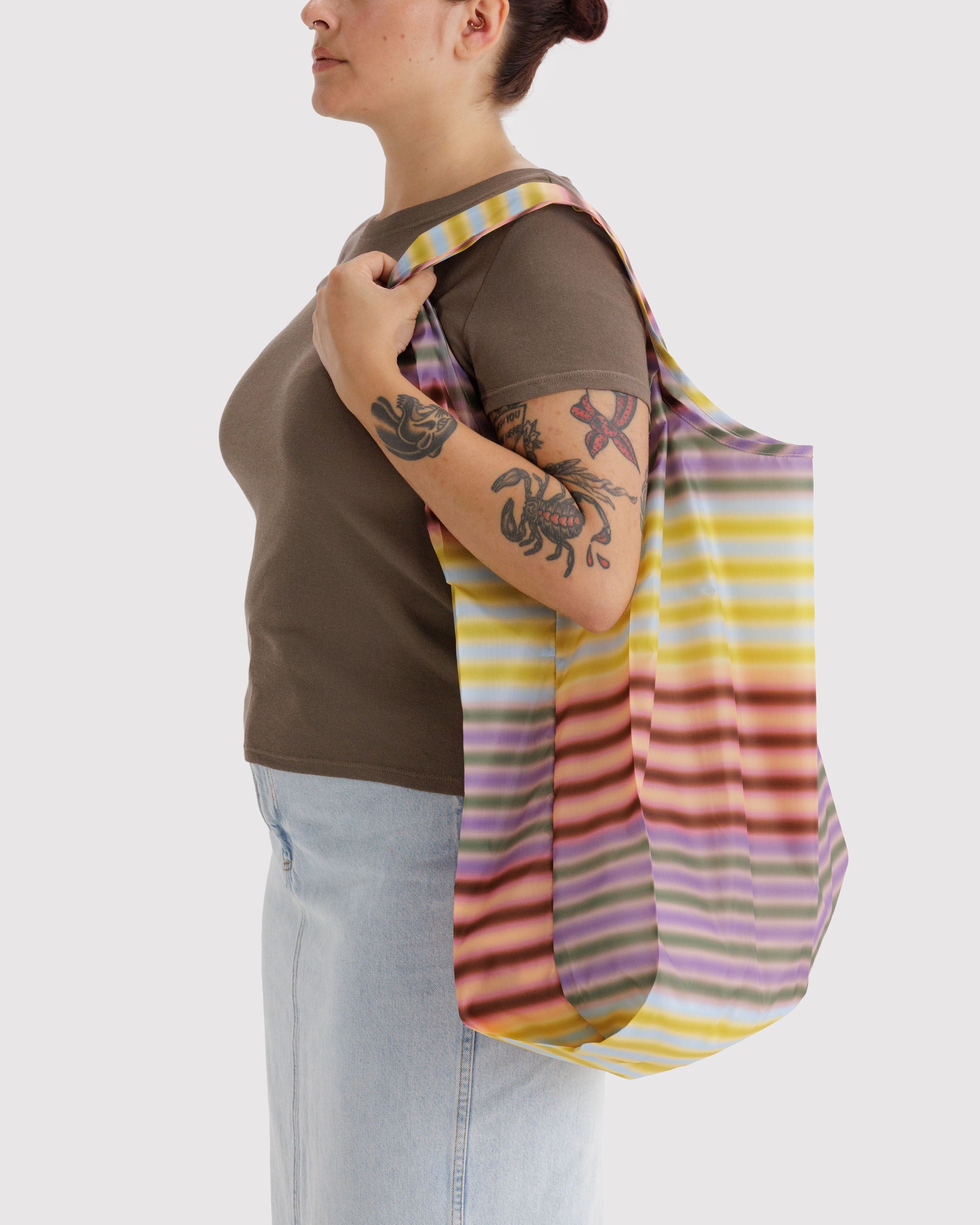 Person carrying a colourful striped bag on shoulder.