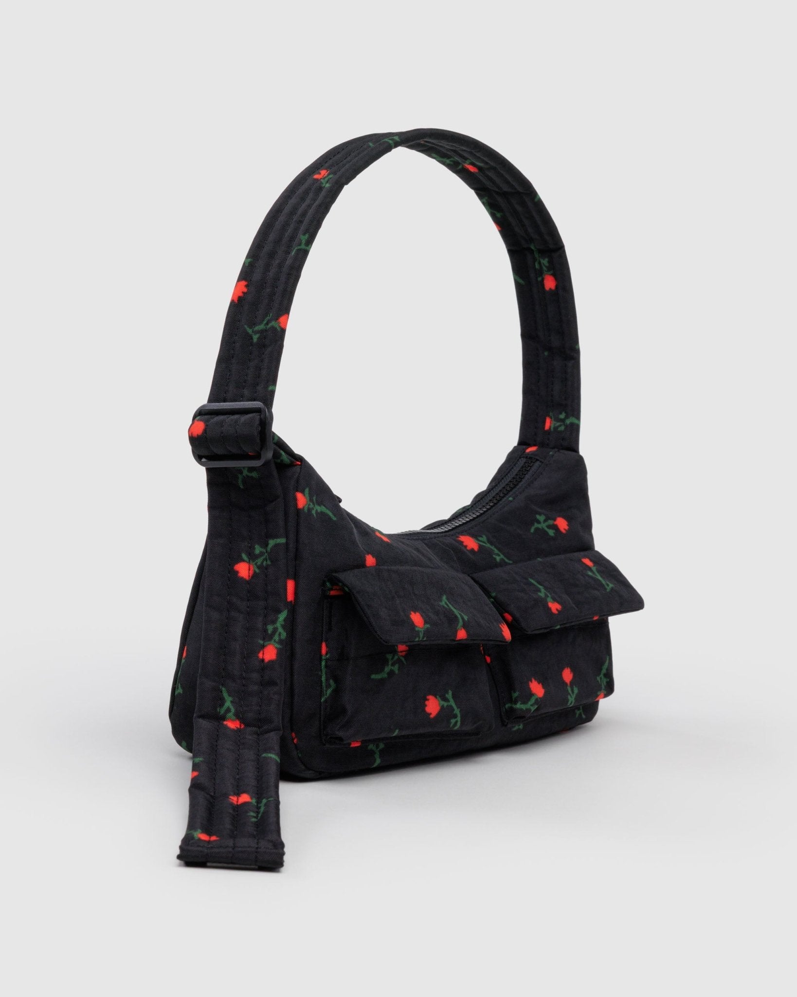 Side of cargo shoulder bag in black with a red wildflower print, adjustable strap and front pockets.