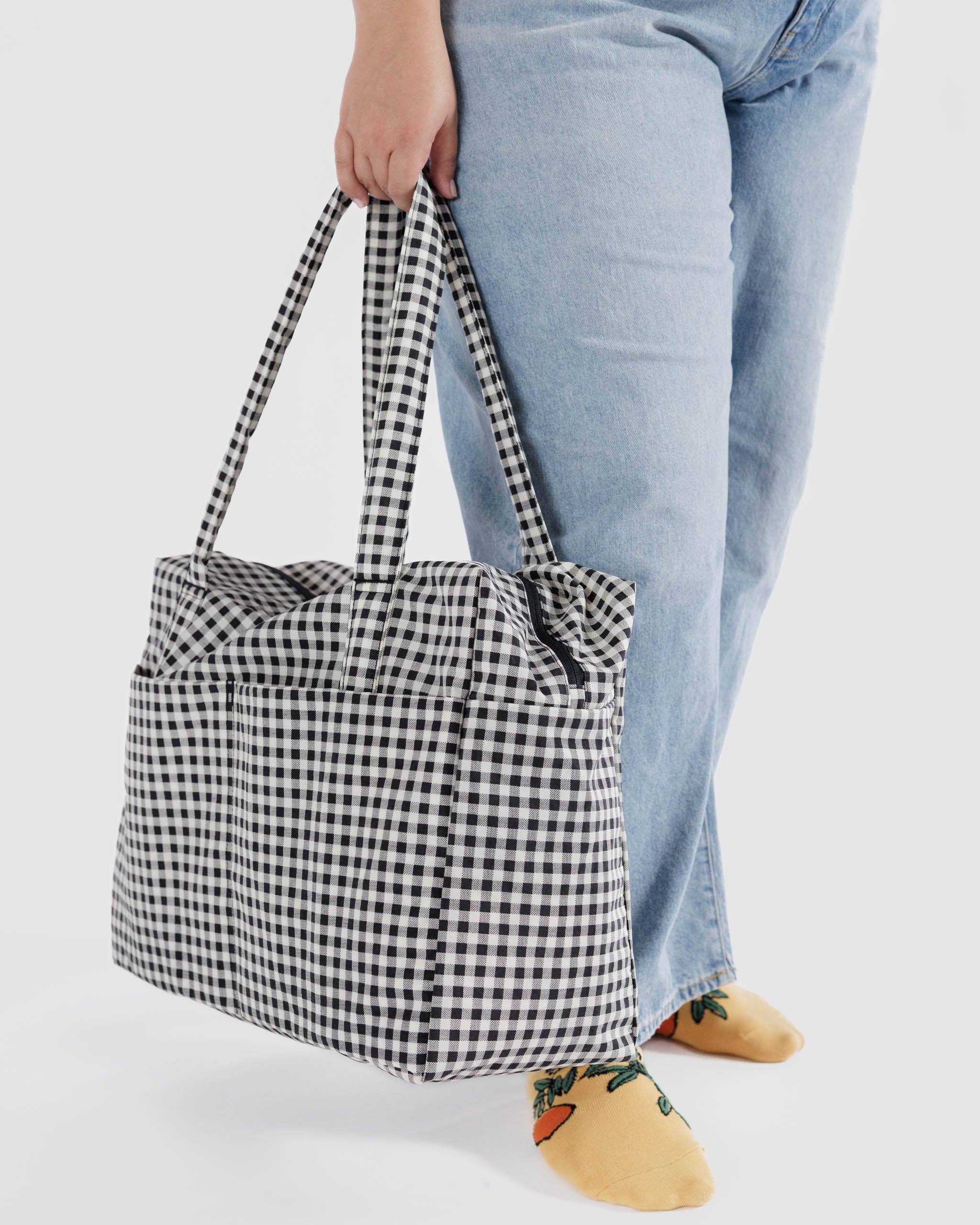 Baggu-cloud-carry-on-in-black-and-white-gingham-in-womans-hand-zipper-top-closed