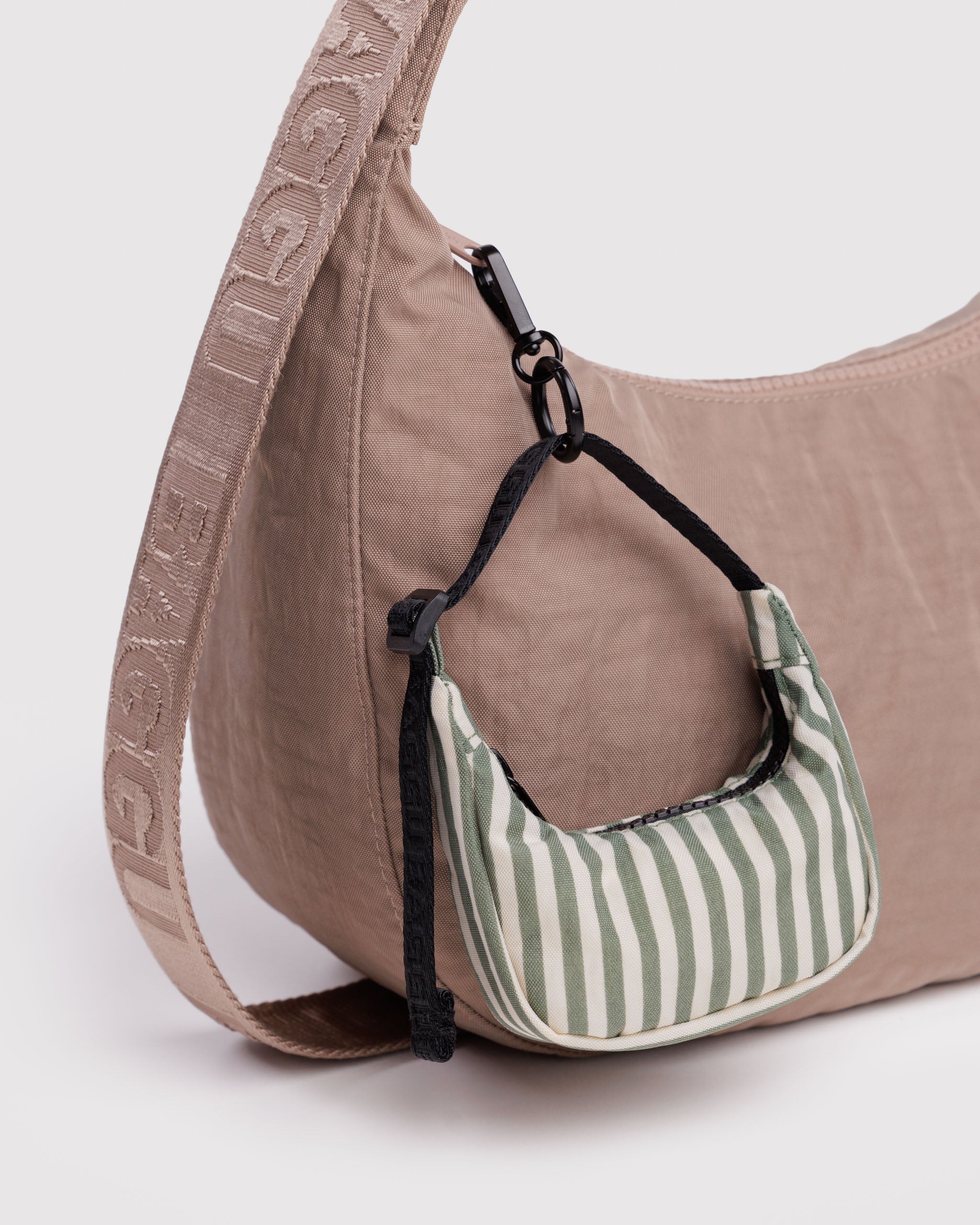 Brown handbag with a green and white striped bag charm attached on by clip to zipper.