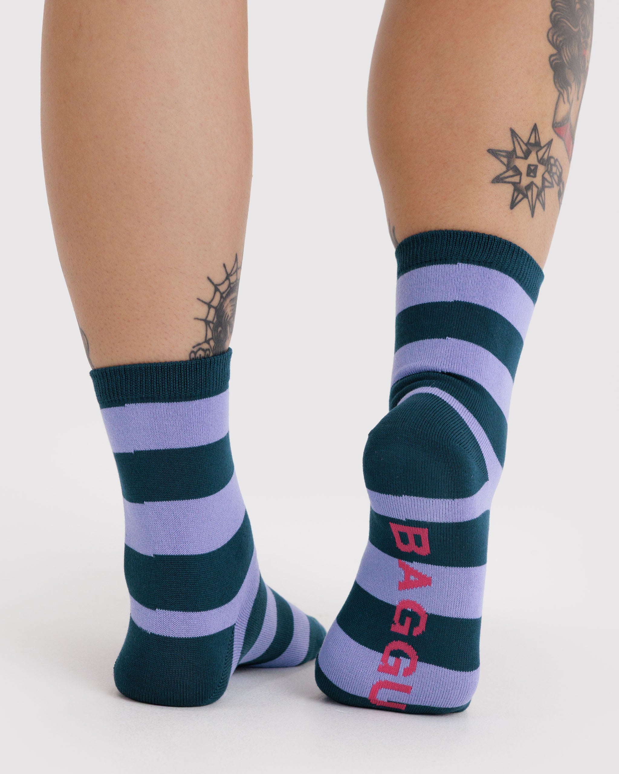 Person wearing striped socks with 'BAGGU' branding on sole.