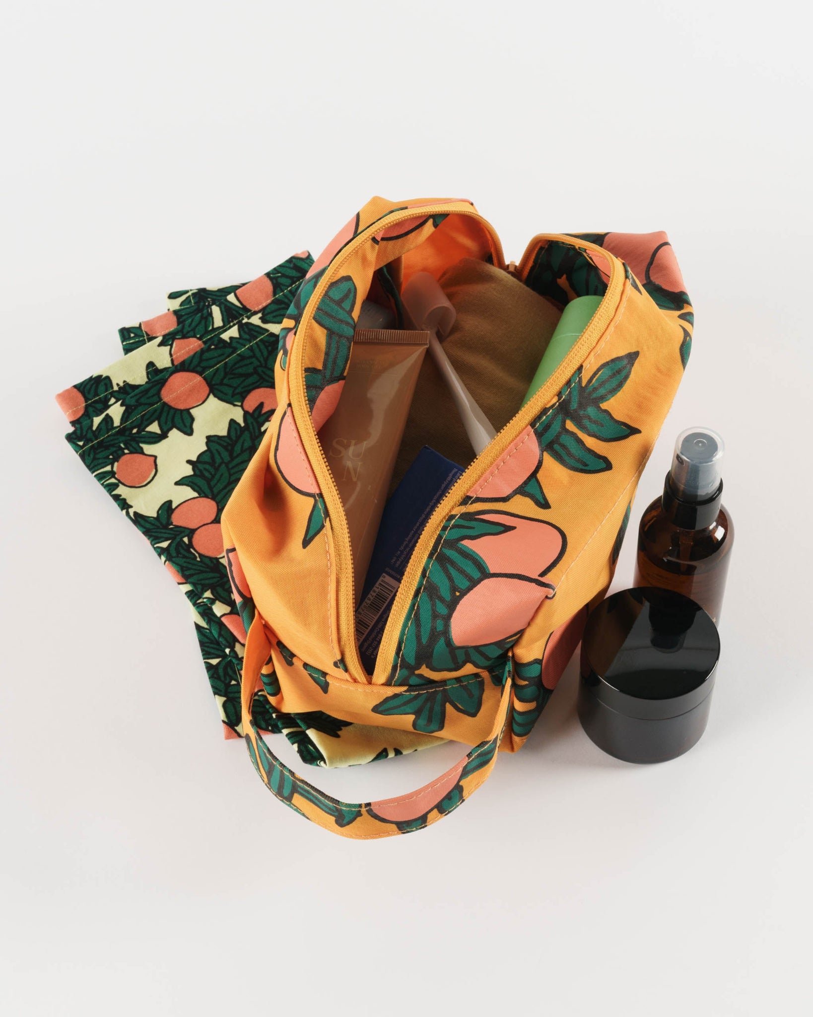 Oranges and green leaves-patterned bag with cosmetic items.