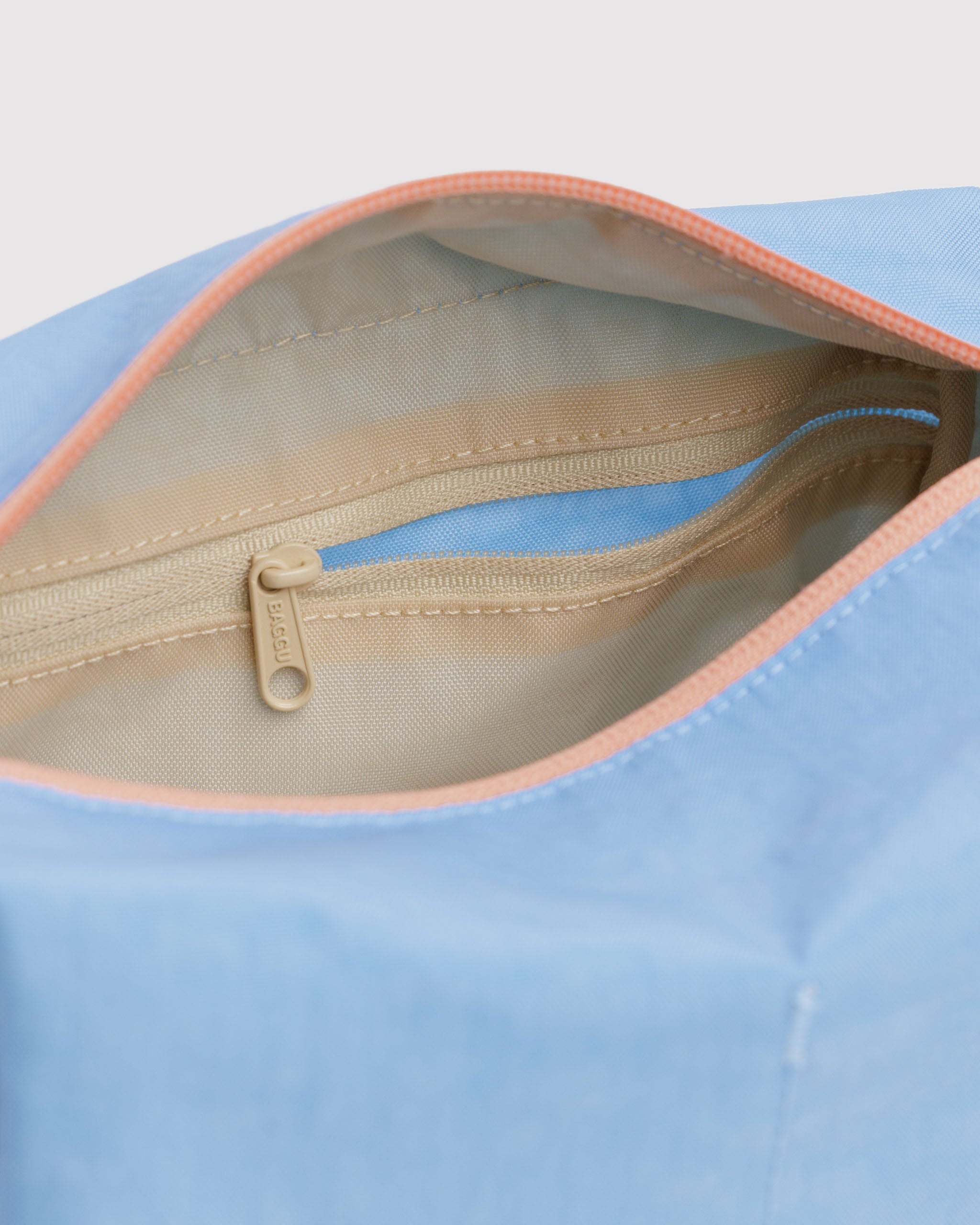 Close-up of a blue bag with a beige interior and zip pocket.