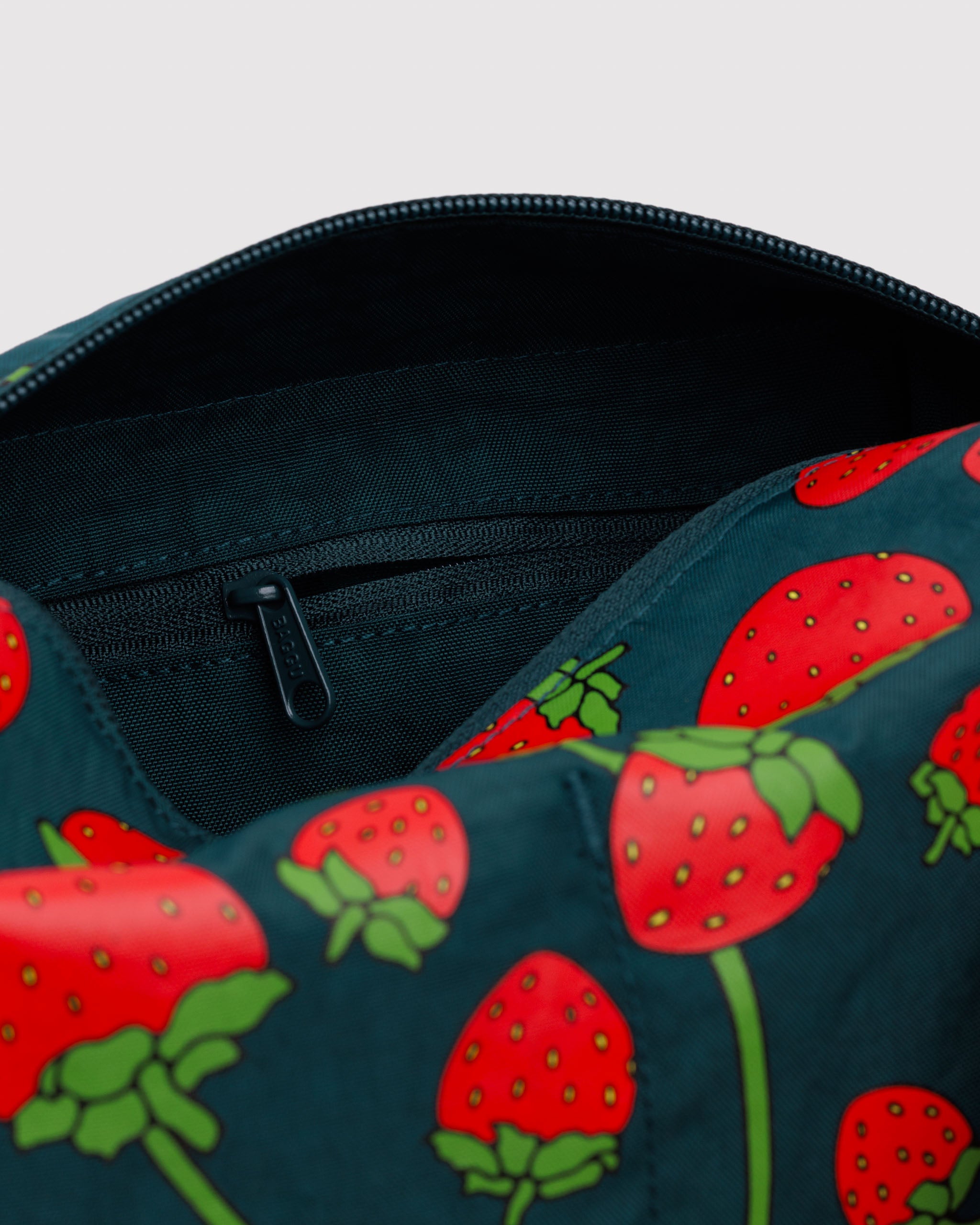 Close up of outside strawberry pattern and interior zip pouch.