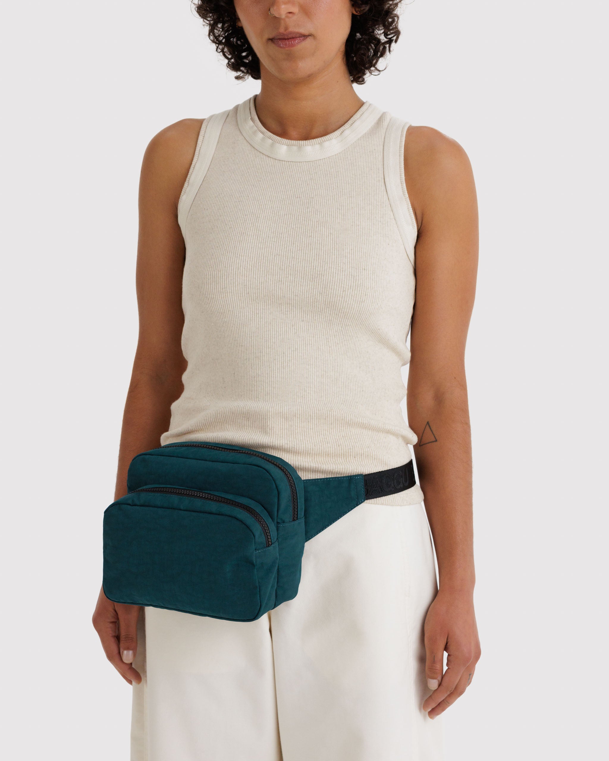 Person wearing a teal fanny pack bag around waist.