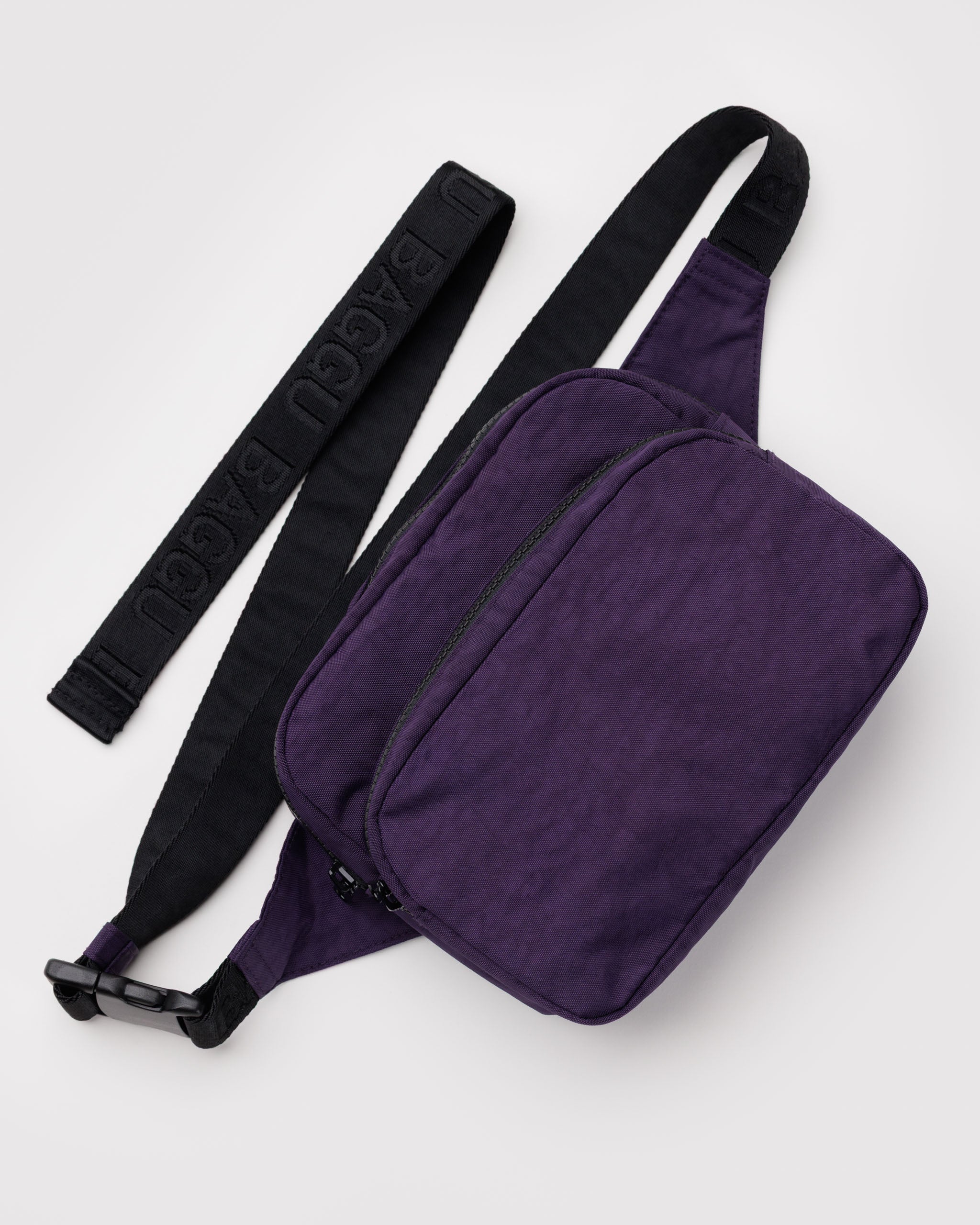 Purple waist bag with black adjustable wide webbed strap and two zip pockets.