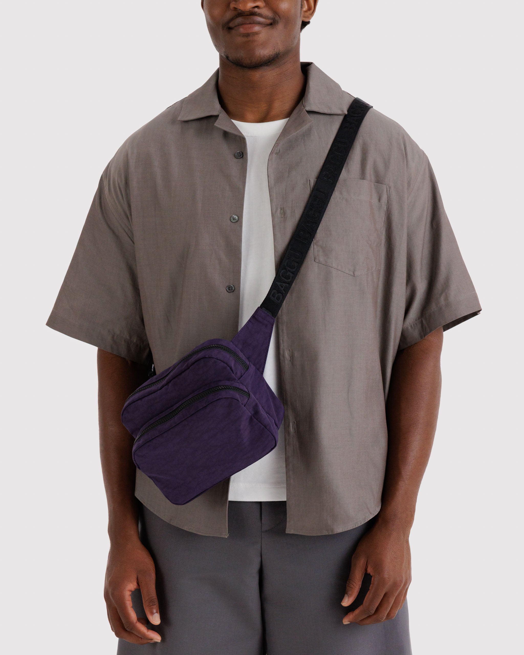 Man wearing a purple crossbody bag over his shoulder.