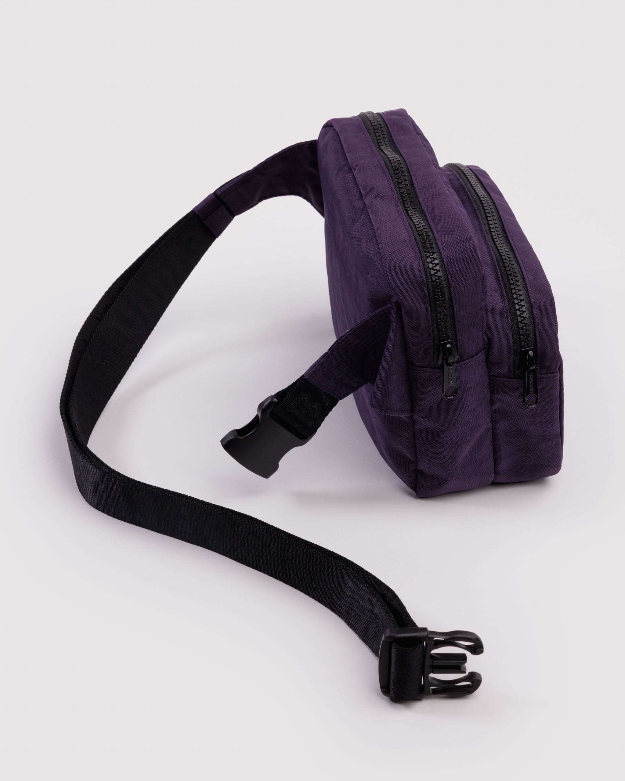 Purple fanny pack with a wide webbed black adjustable strap and two zippered pockets.
