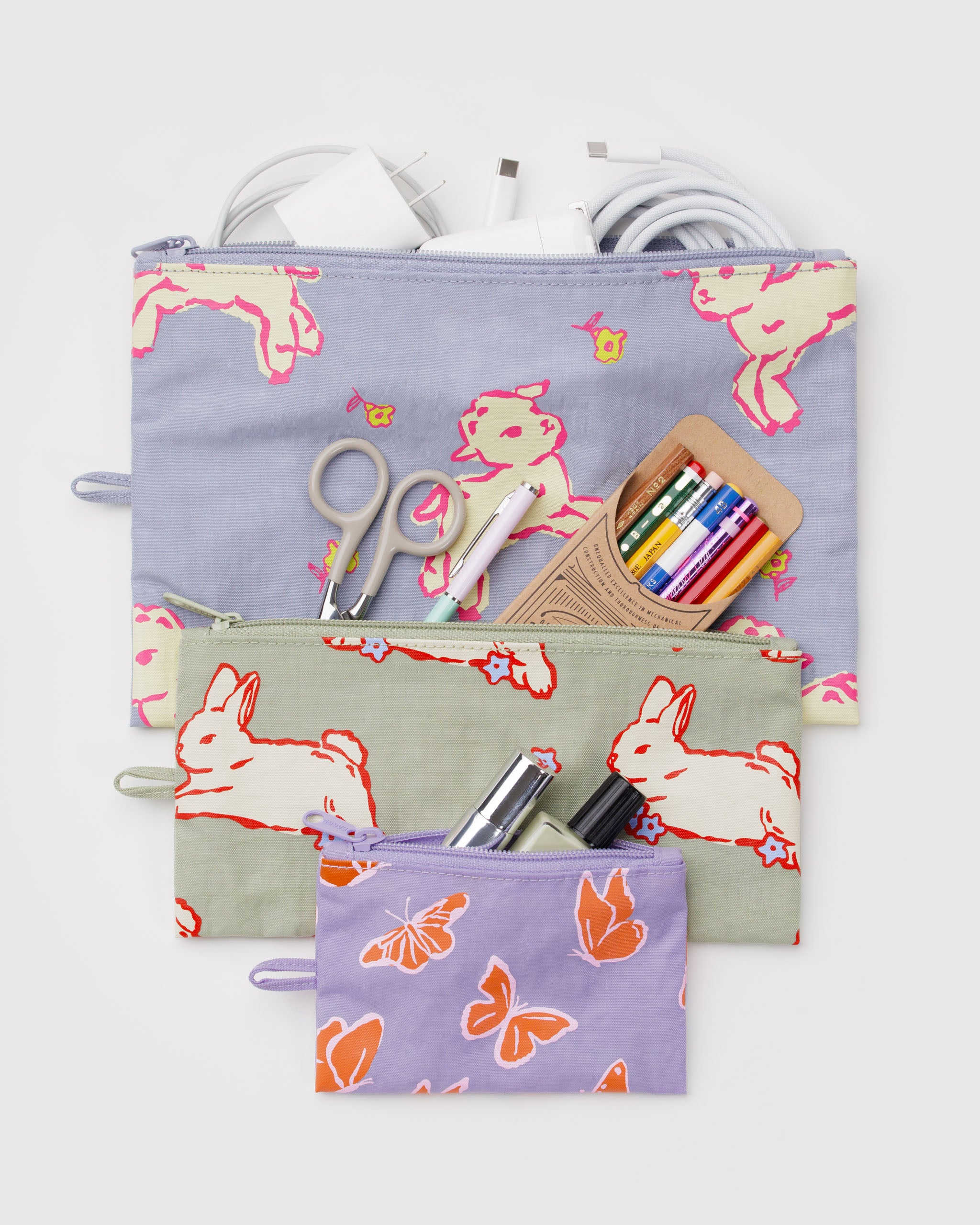 Set of three zip top pouches in different sizes with rabbit, lamb and butterfly patterns, containing stationery items with a hanging loop at the side.