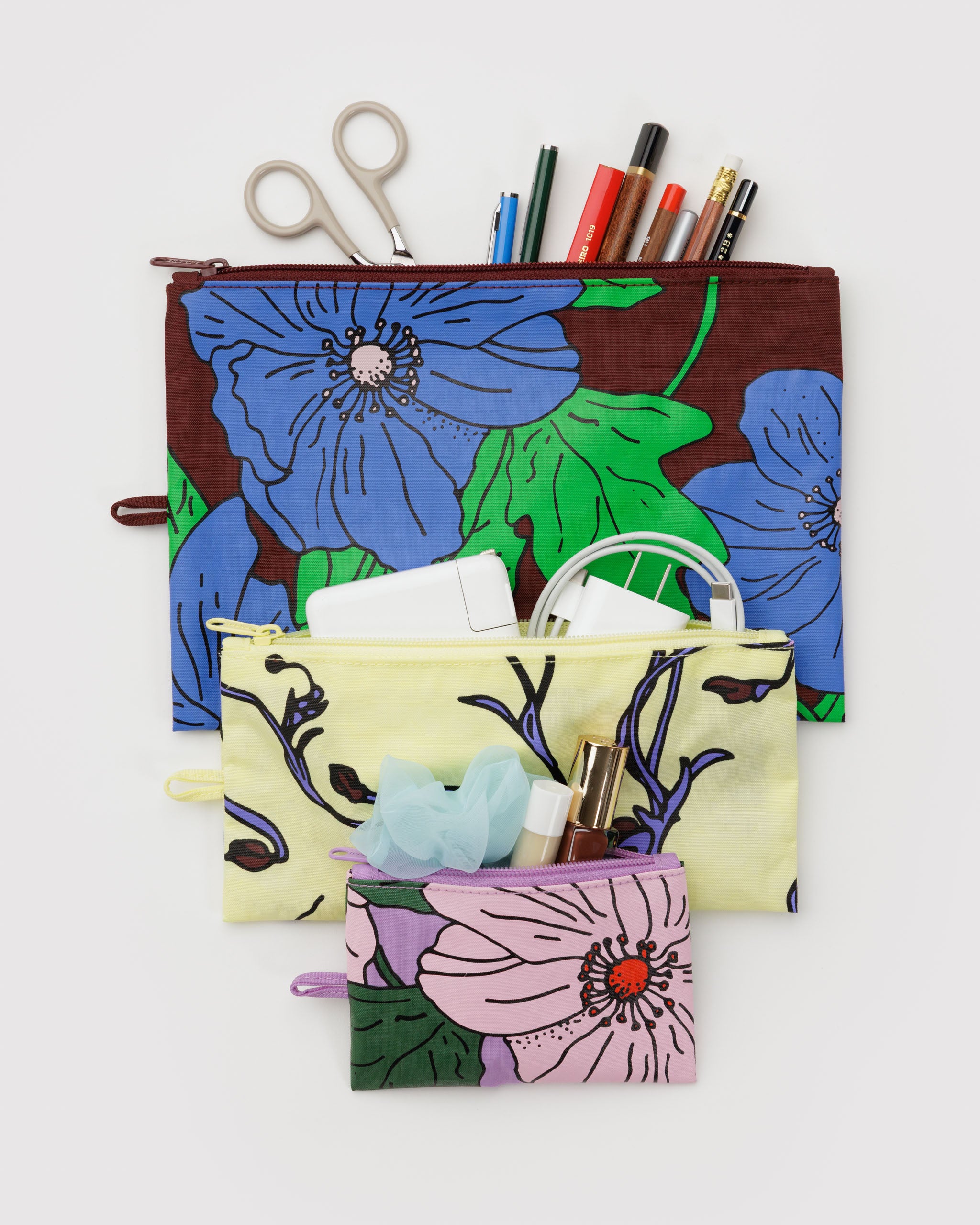 Set of floral poppy zip pouches with stationery items lying on table.