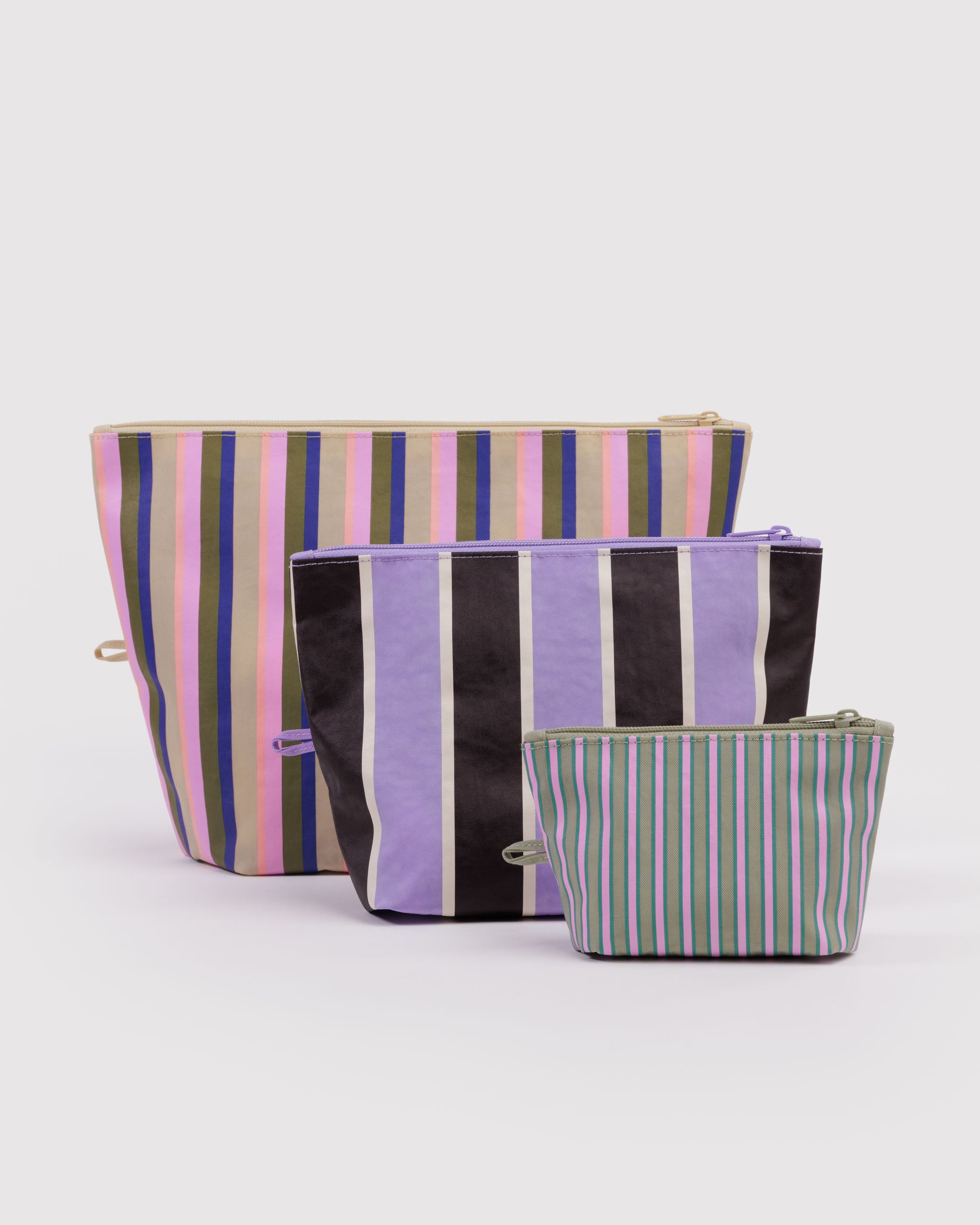 Three different sized and pastel striped, expanded zip top pouches with items inside, hanging loop and standing upright on flat bottom.