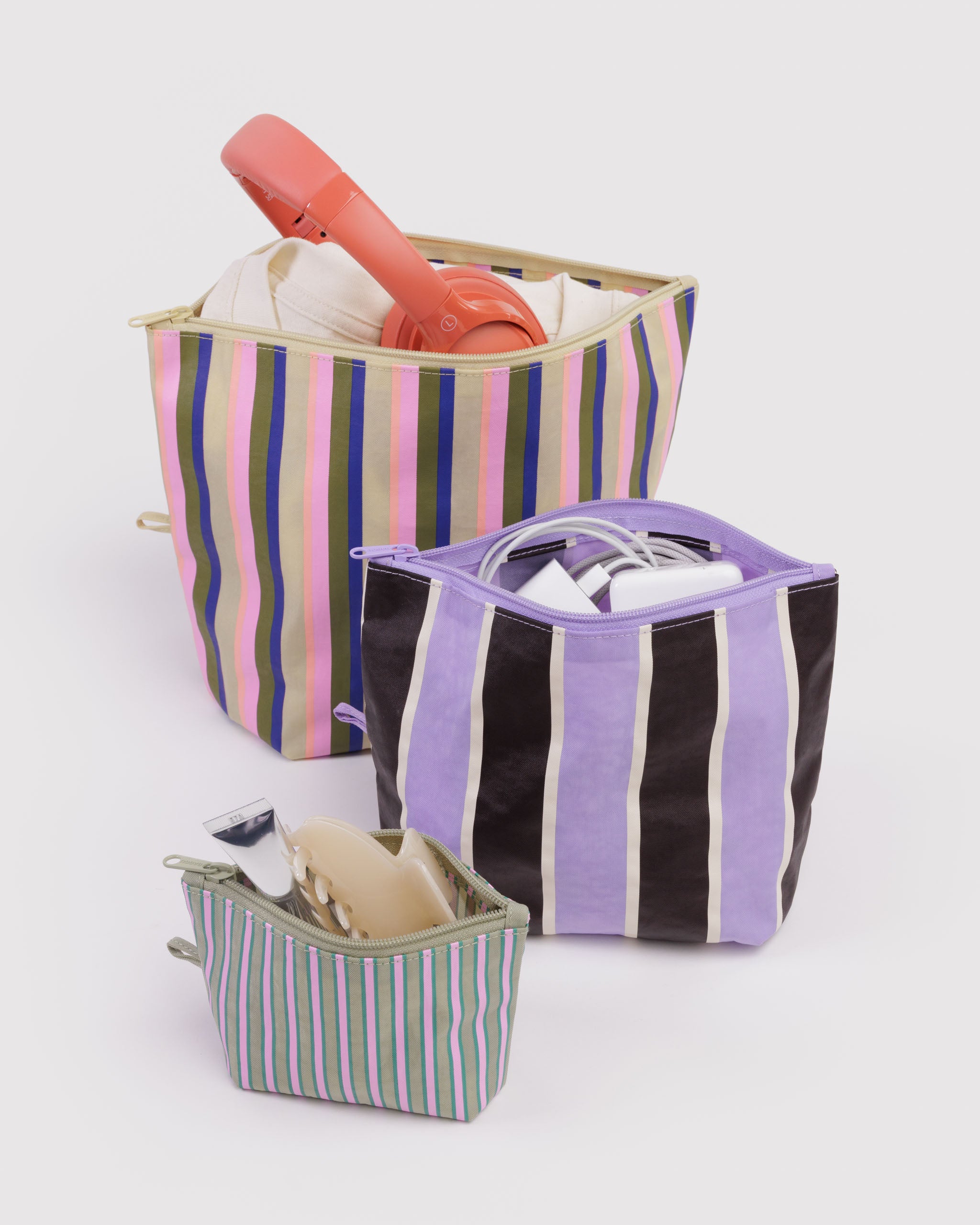Set of 3 different sized striped bags with zip top open with items inside and standing on expandable base.