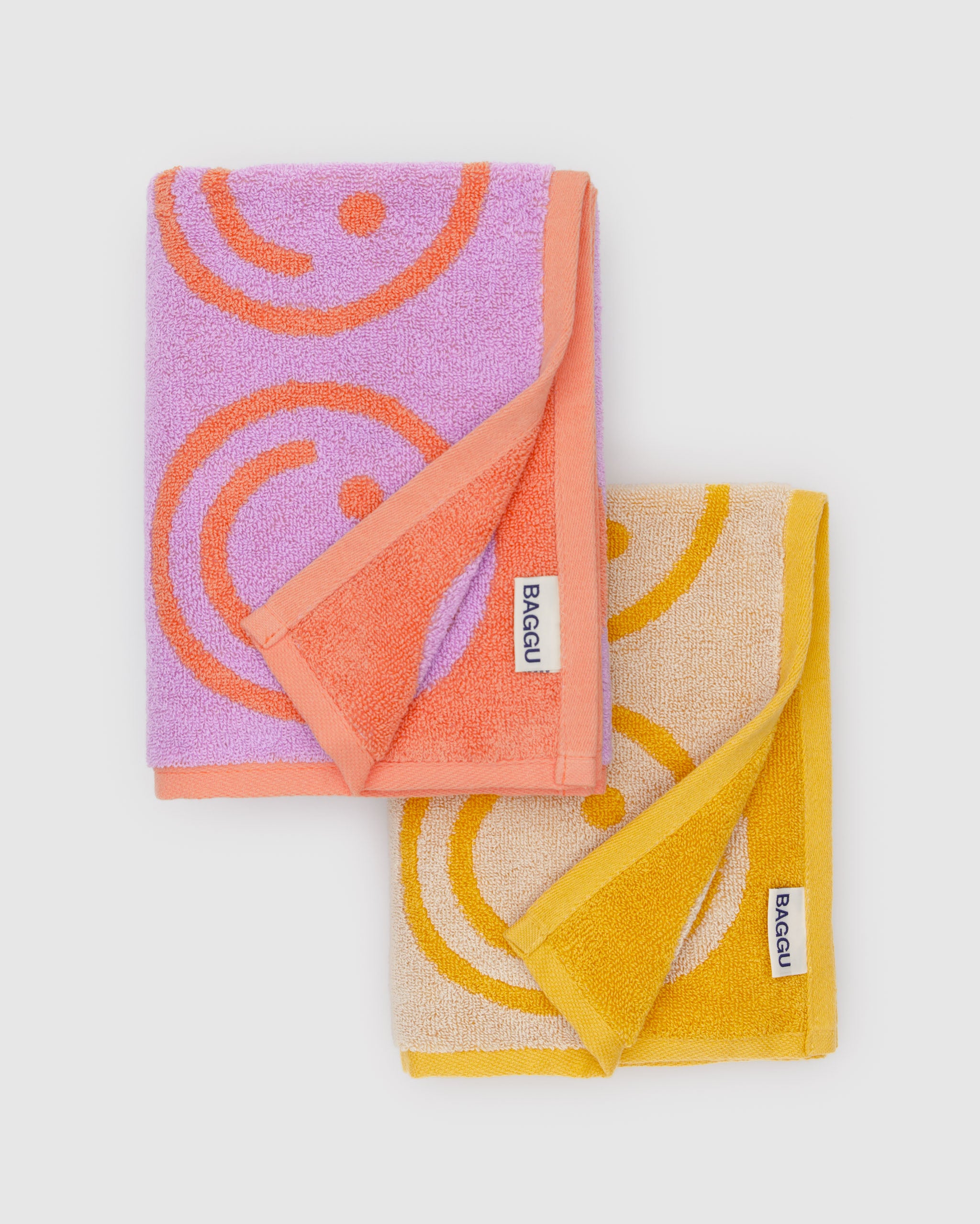 smiley-face-pattern-on-towels-with-contrast-colour-at-edge-in-colours-lilac-orange-and-marigold-cream-baggu-logo