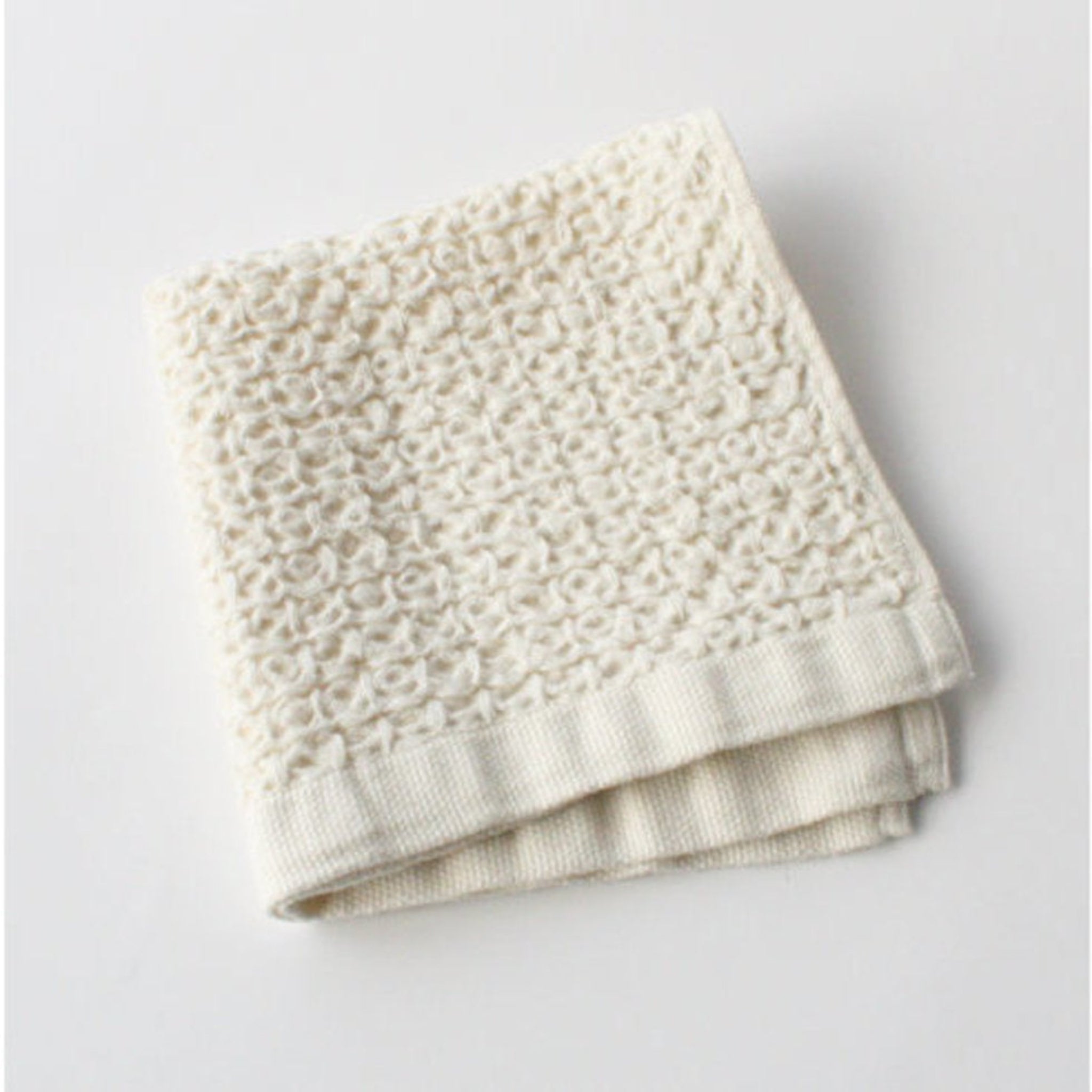 Folded cream-coloured waffle textured towel.