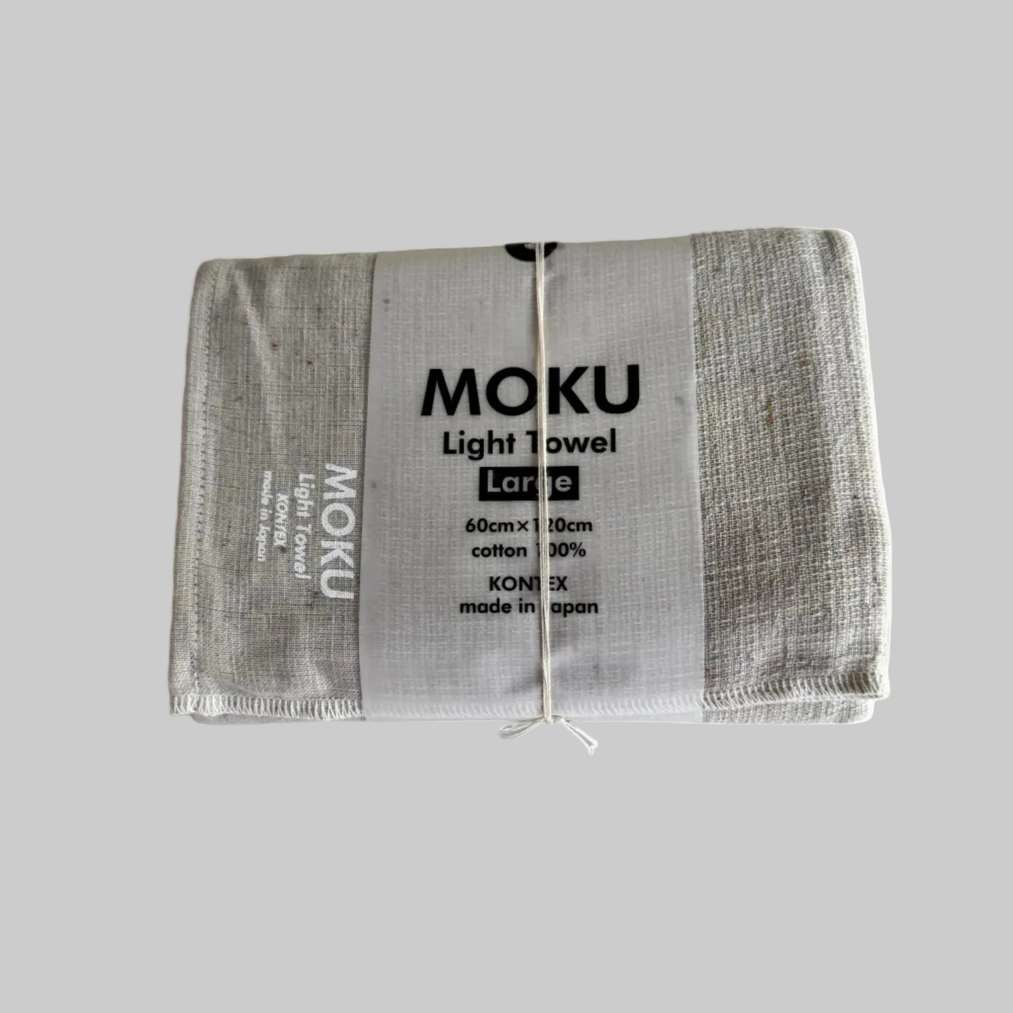 Moku light bath towel in a natural colour folded with a packaging sleeve and with white writing "MOKU Light Towel' on fabric.