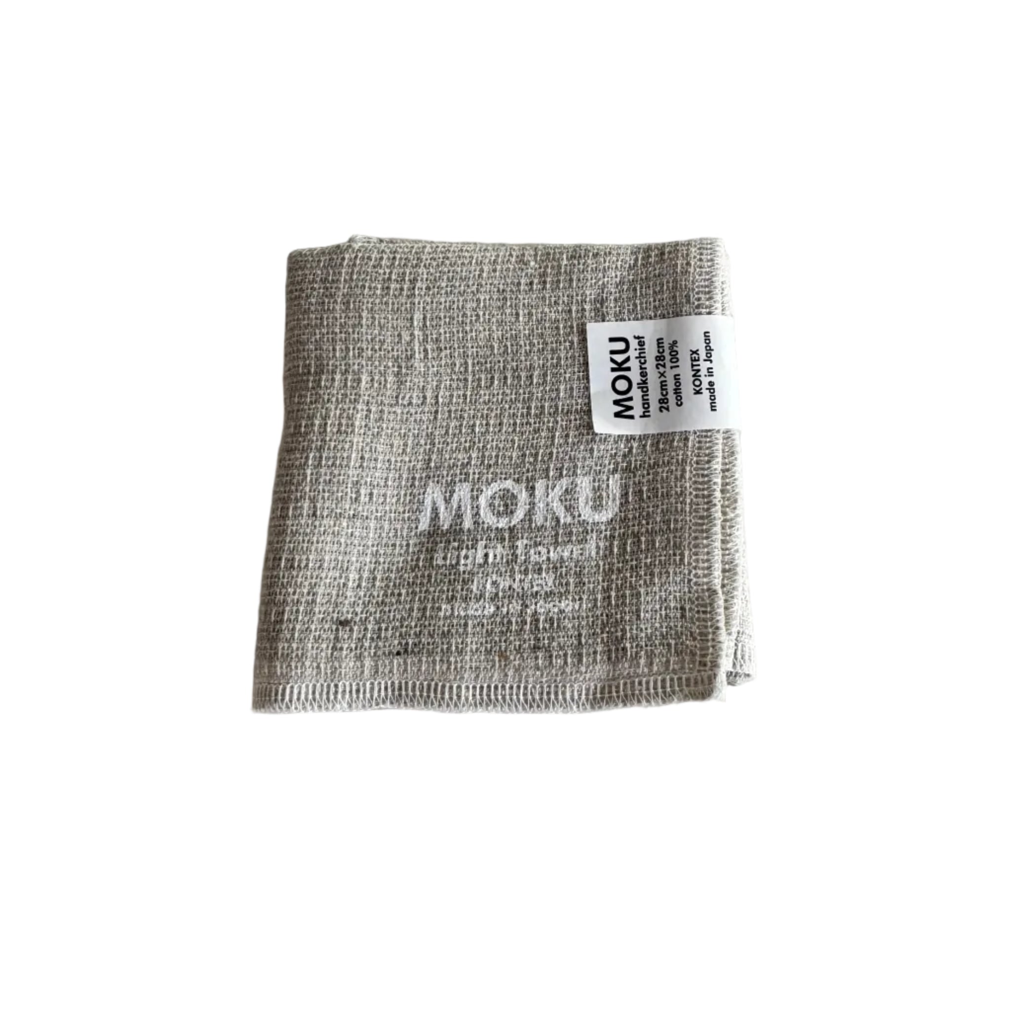 Folded natural face washer with 'MOKU Light Towel' written in white and a label.