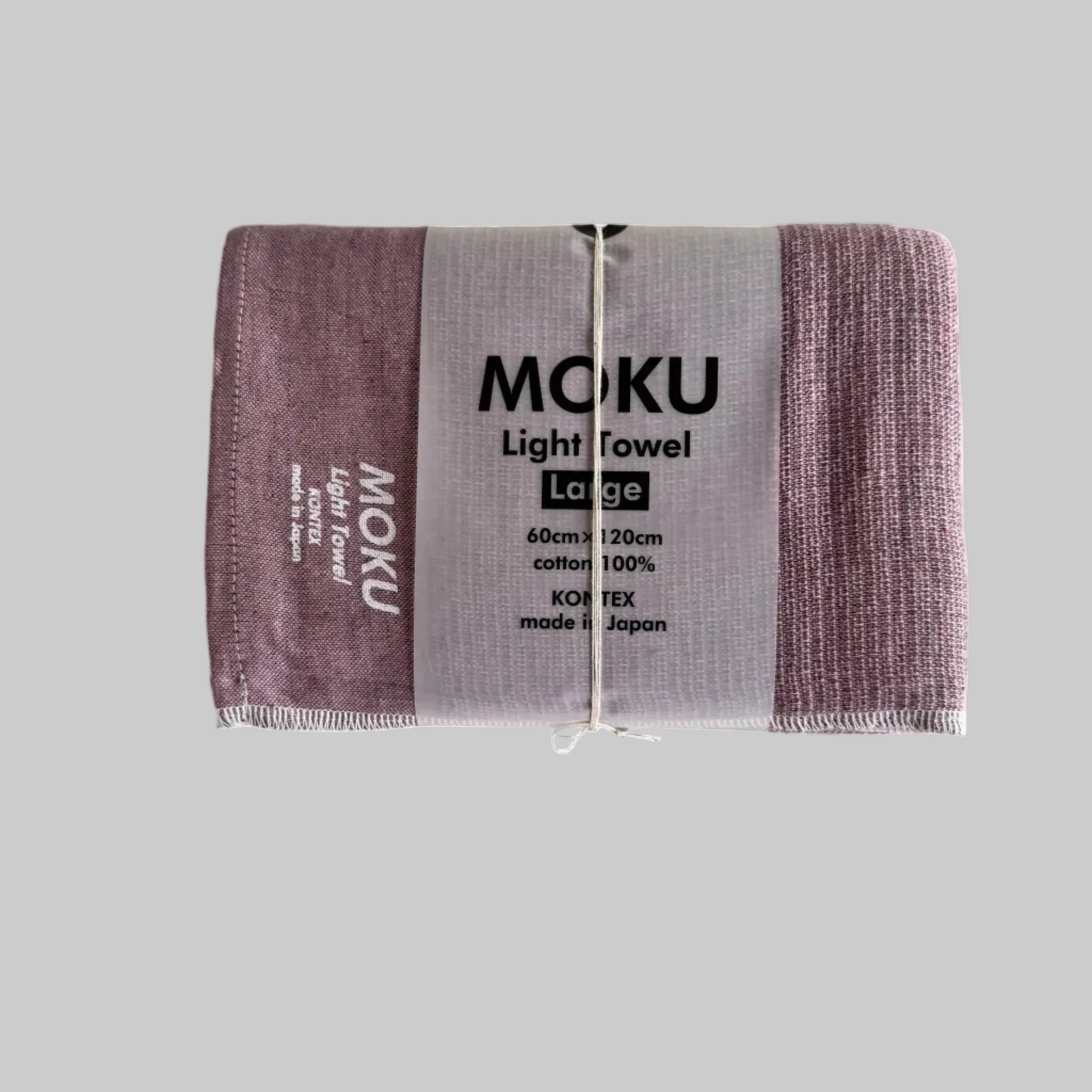 Moku light bath towel in a pink colour folded with a packaging sleeve and with white writing "MOKU Light Towel' on fabric.
