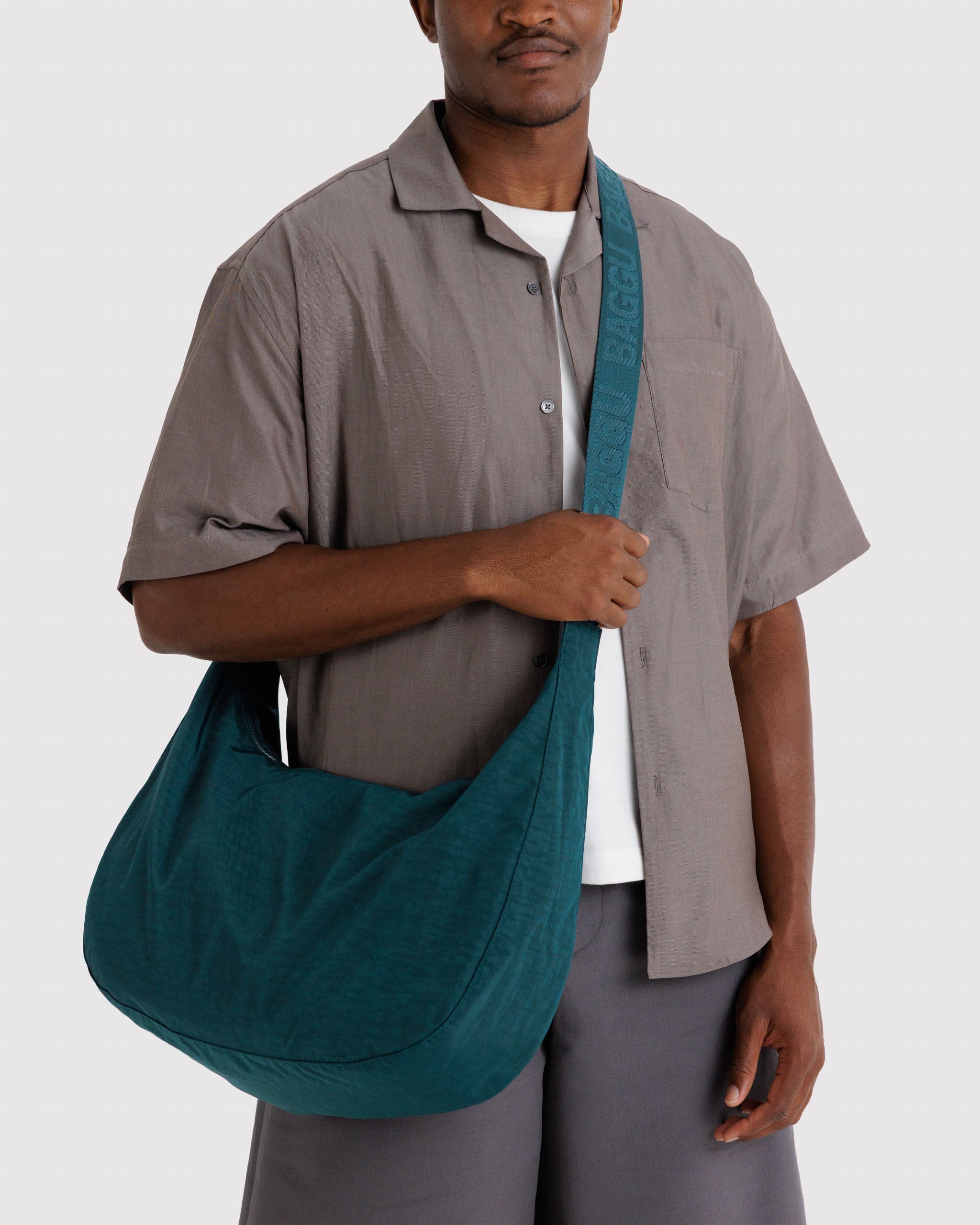 Man wearing a teal bag with wide adjustable strap crossbody style.