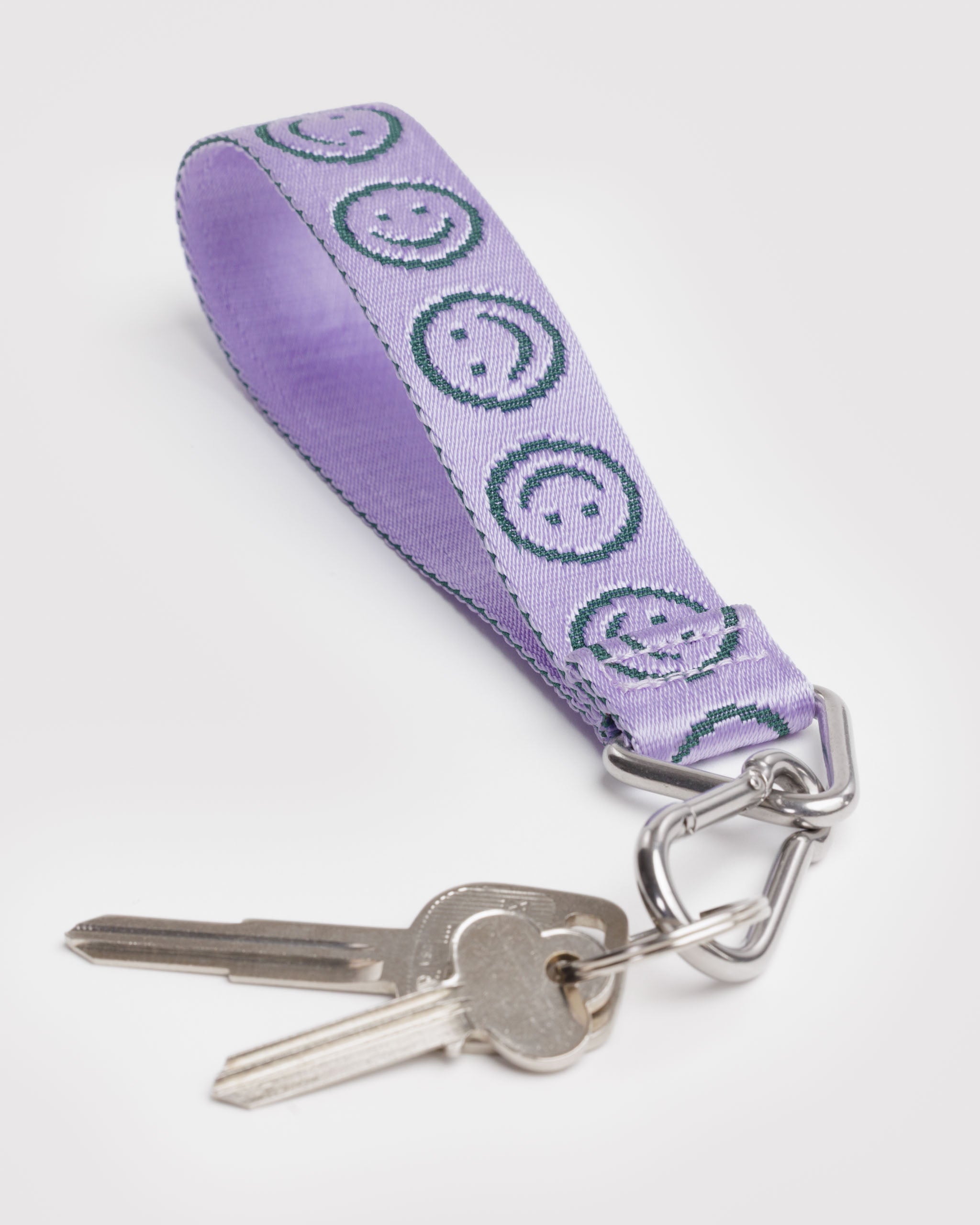 Lilac keychain with green smiley face pattern and keys attached to metal clip.