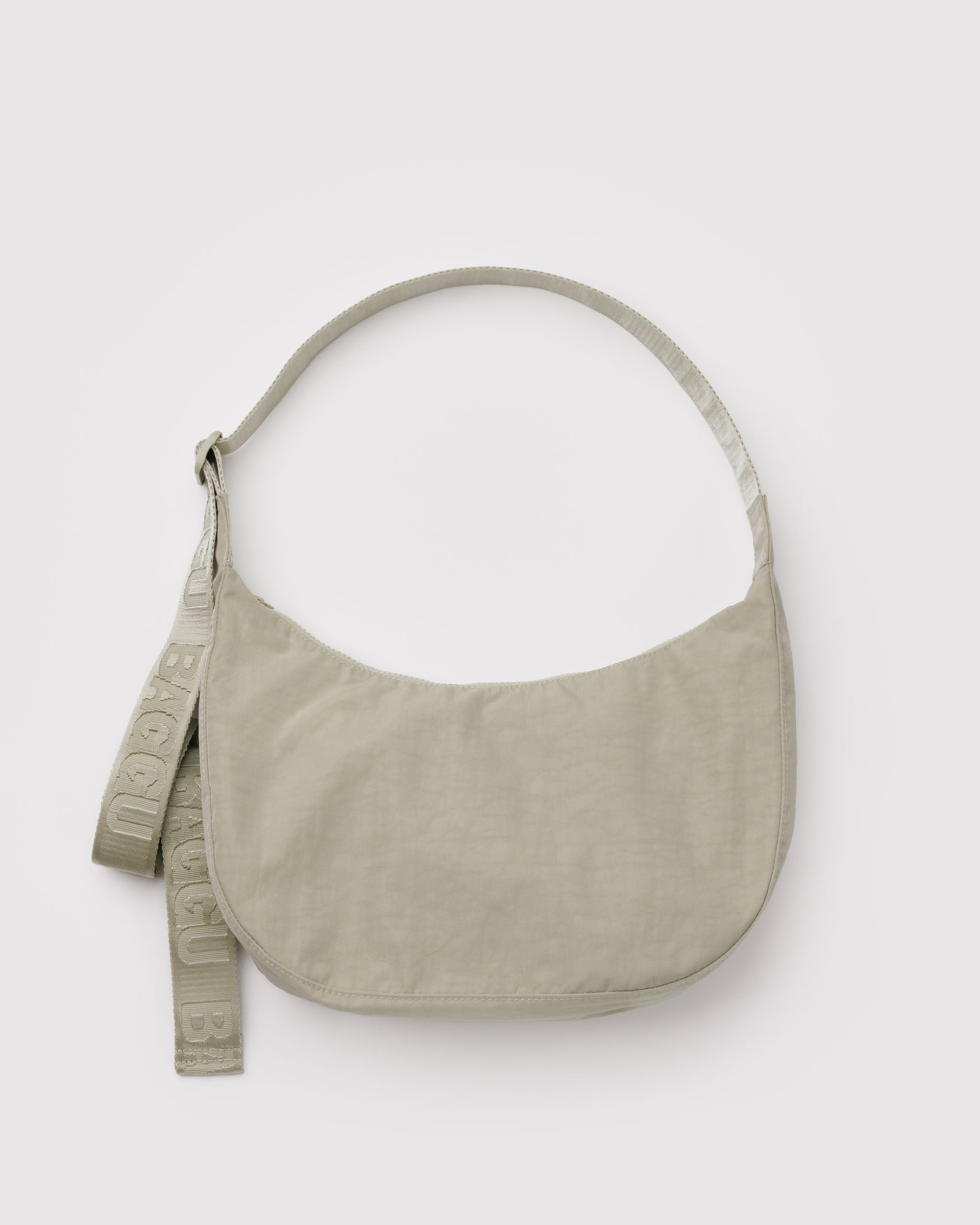 Light green shoulder bag in a crescent shape with a long, wide webbed adjustable strap and top zip.