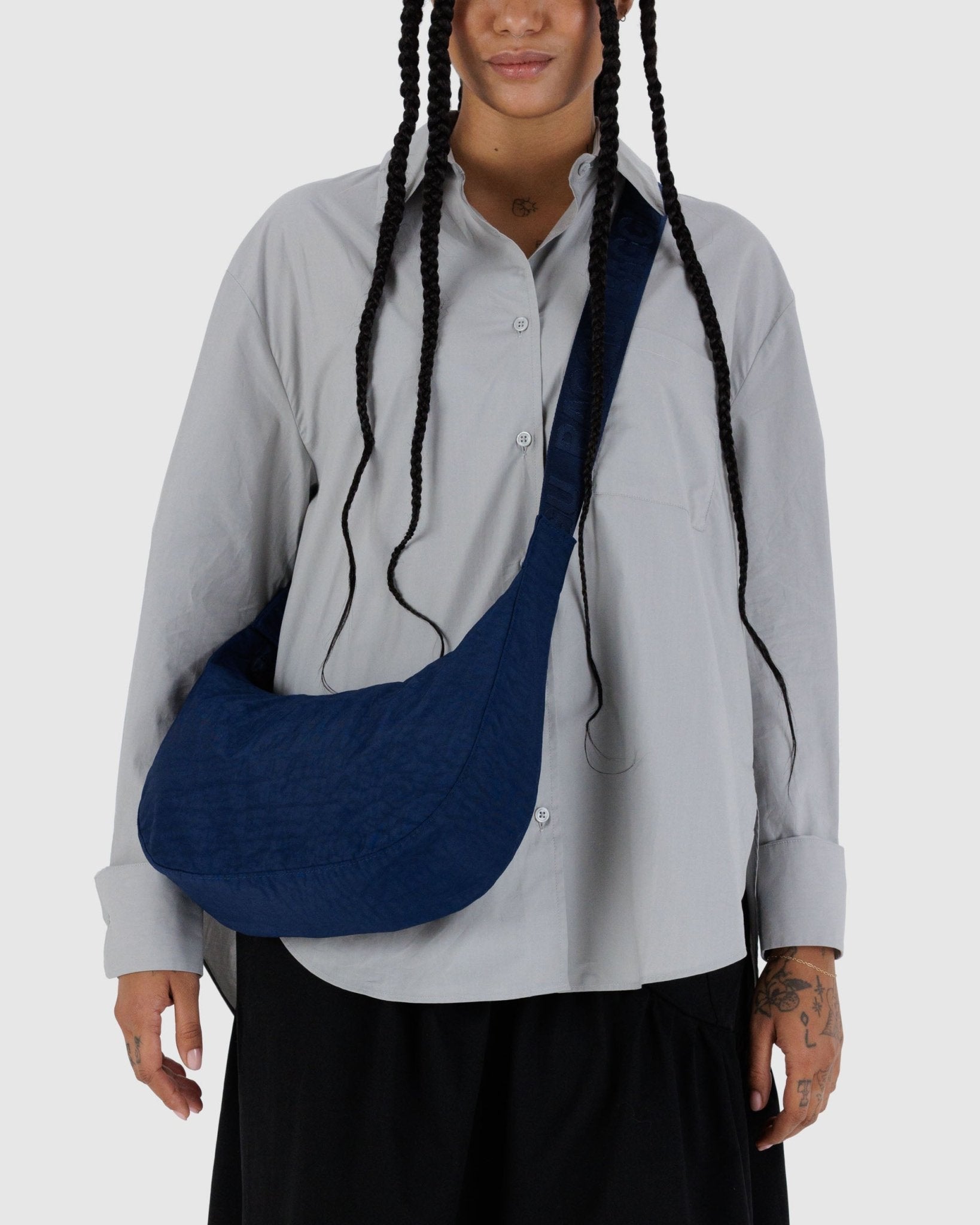 Person wearing a Baggu Medium Nylon Crescent Bag in navy with navy strap crossbody.