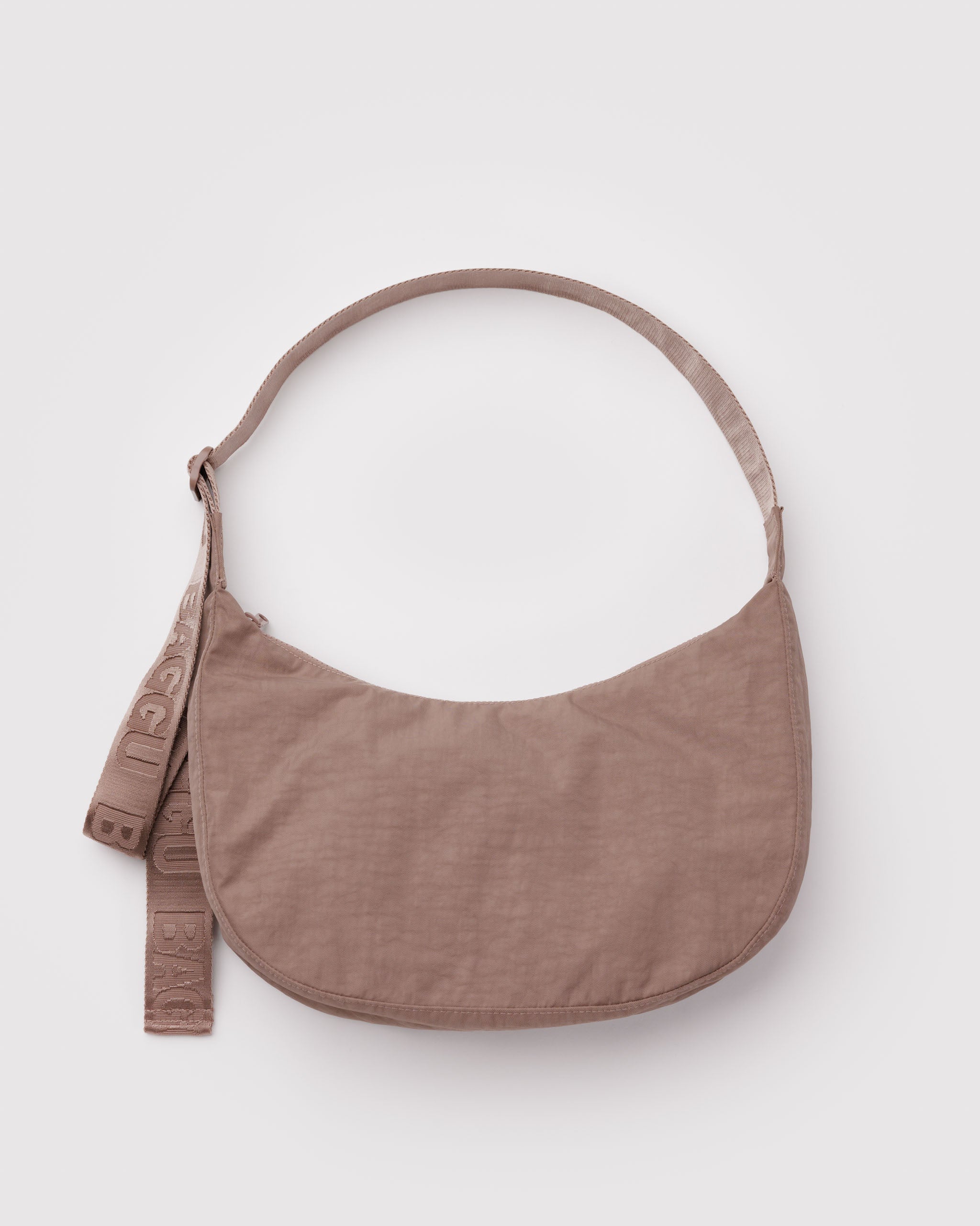 Brown crossbody bag in a crescent shape with a wide webbed adjustable strap and top zip.