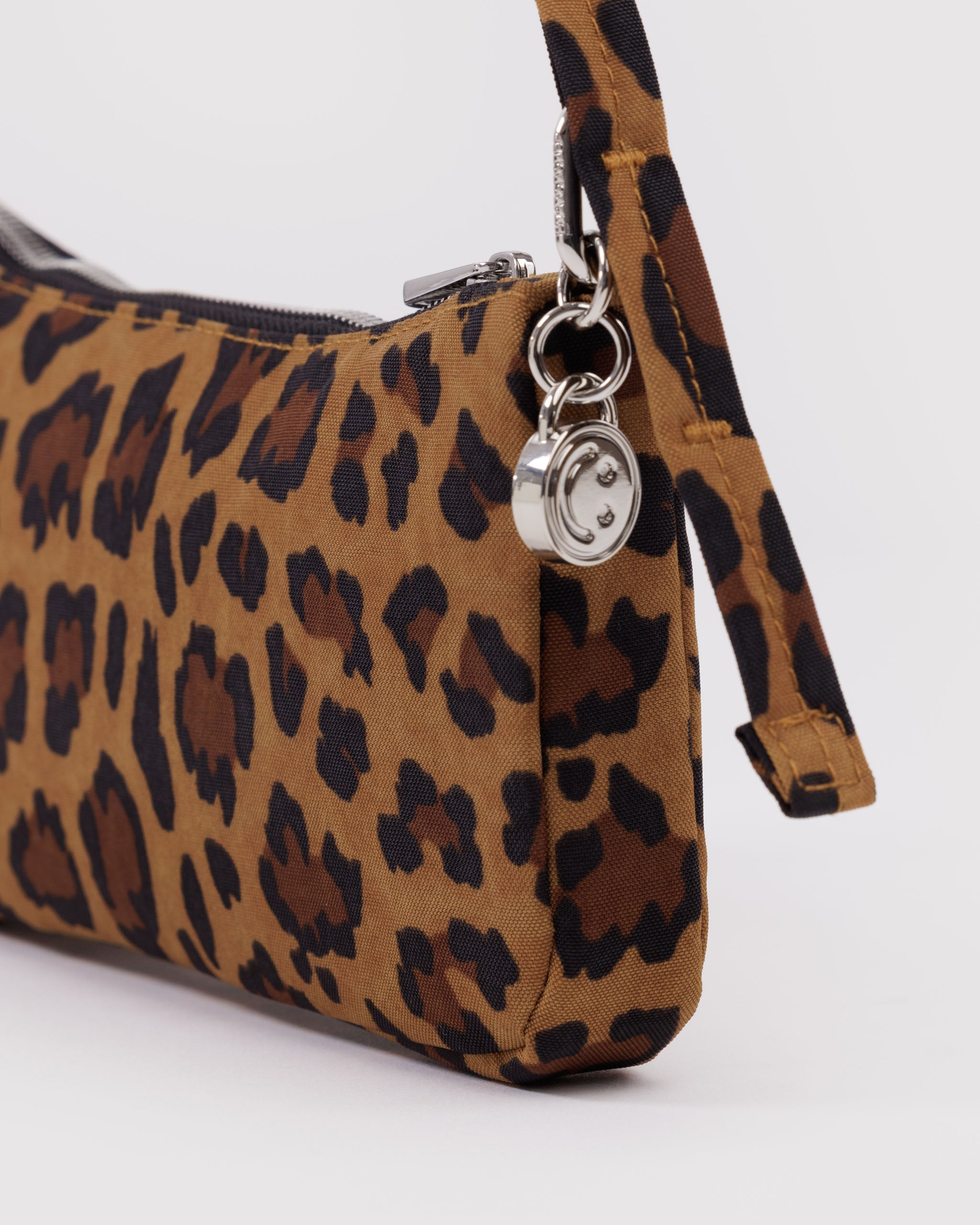 Leopard print handbag with a silver smiley face bag charm attached to metal clasp.