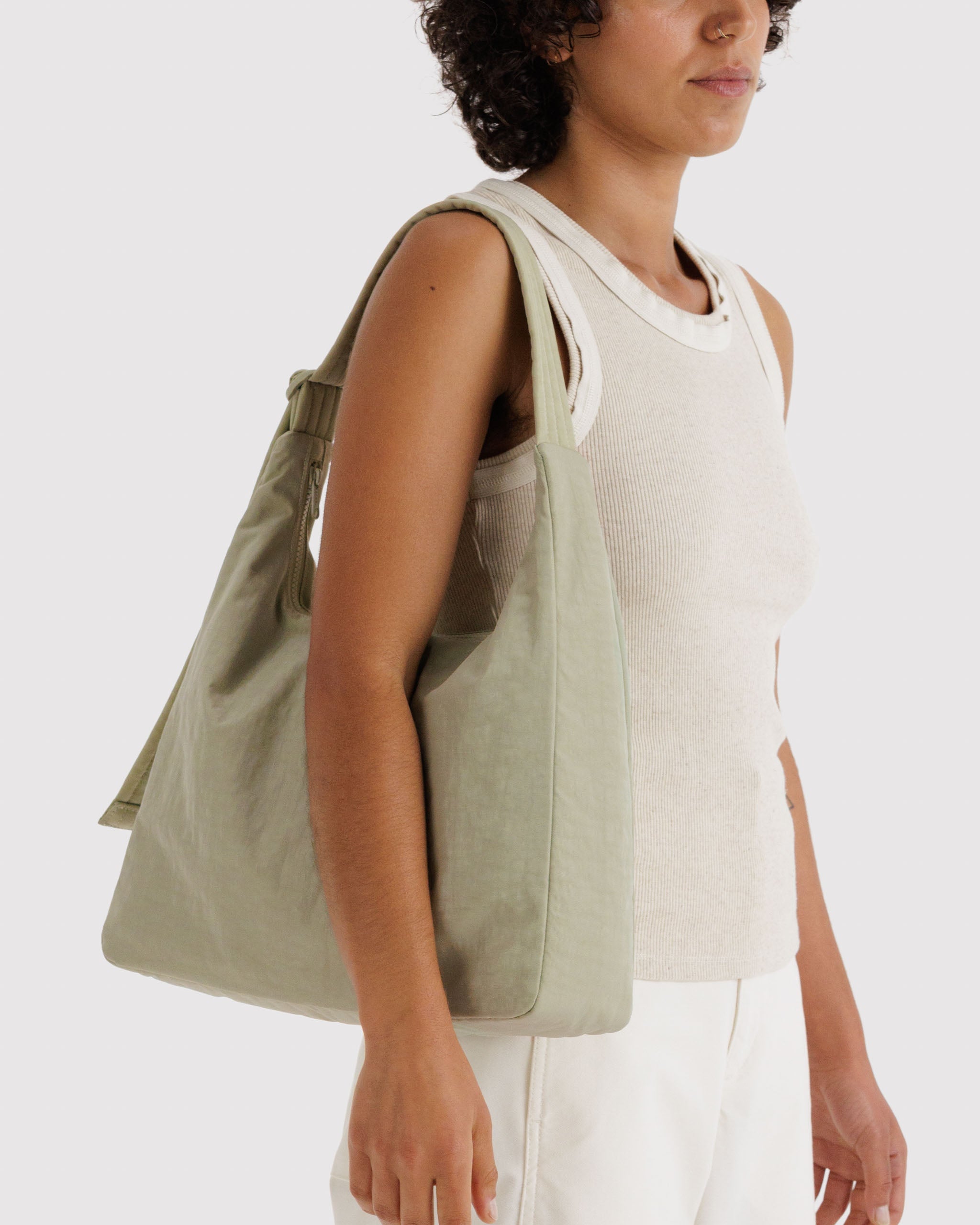 Person holding a green tote bag on shoulder.