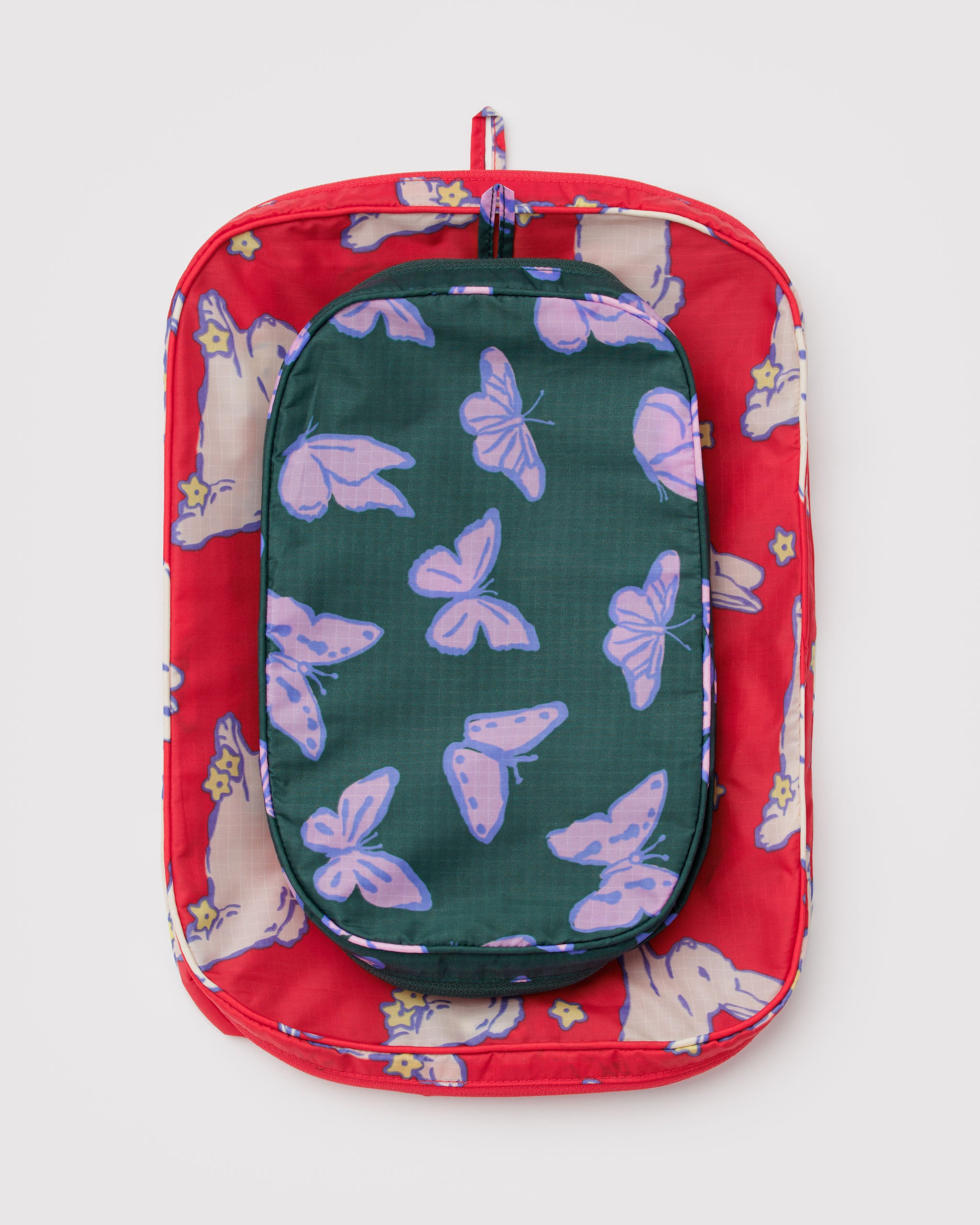 Two empty packing cubes in red with white bunnies and teal with purple butterflies patterns stacked on each other with a hanging loop at top.