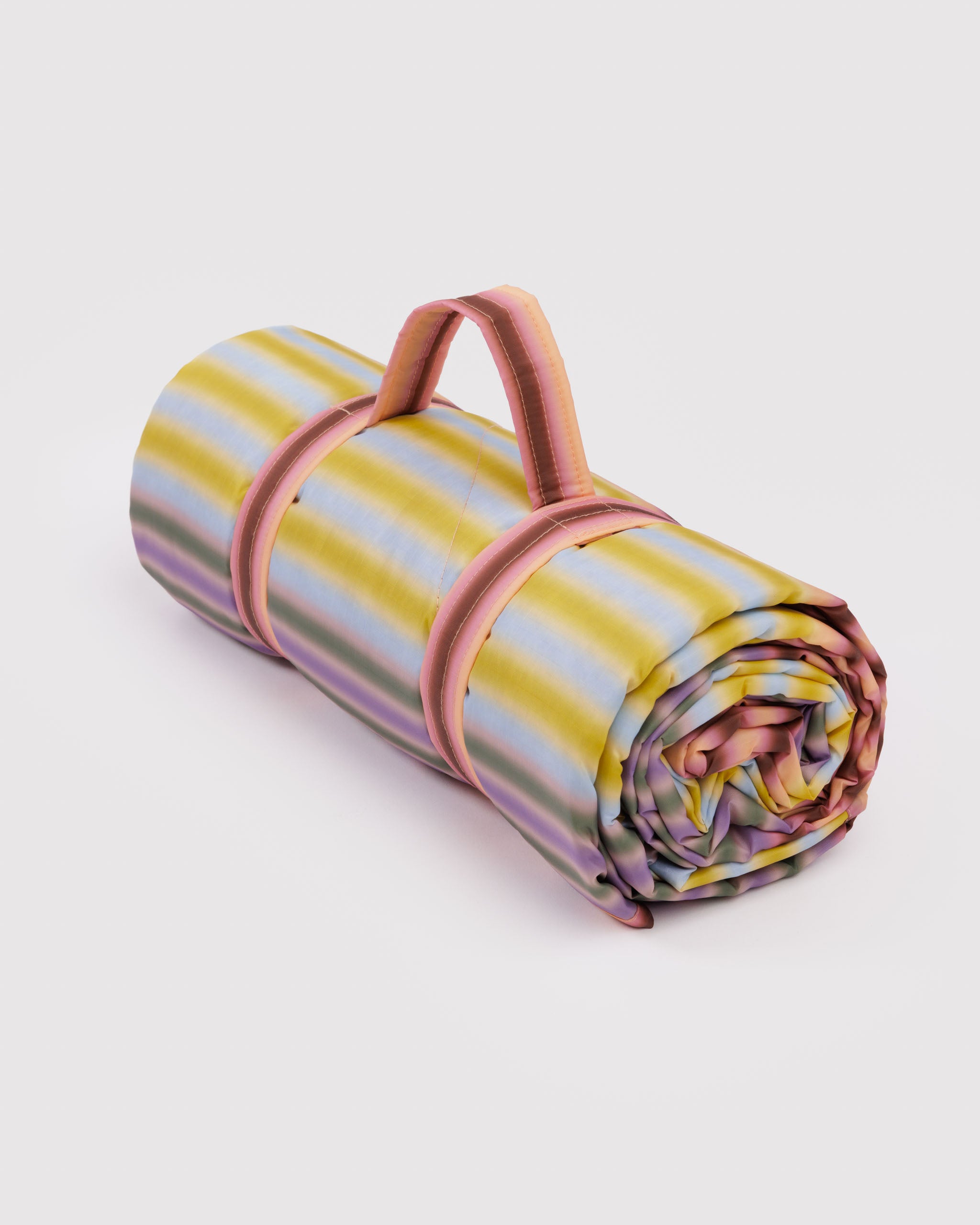 Rolled-up picnic blanket with carry handle in colourful stripes.