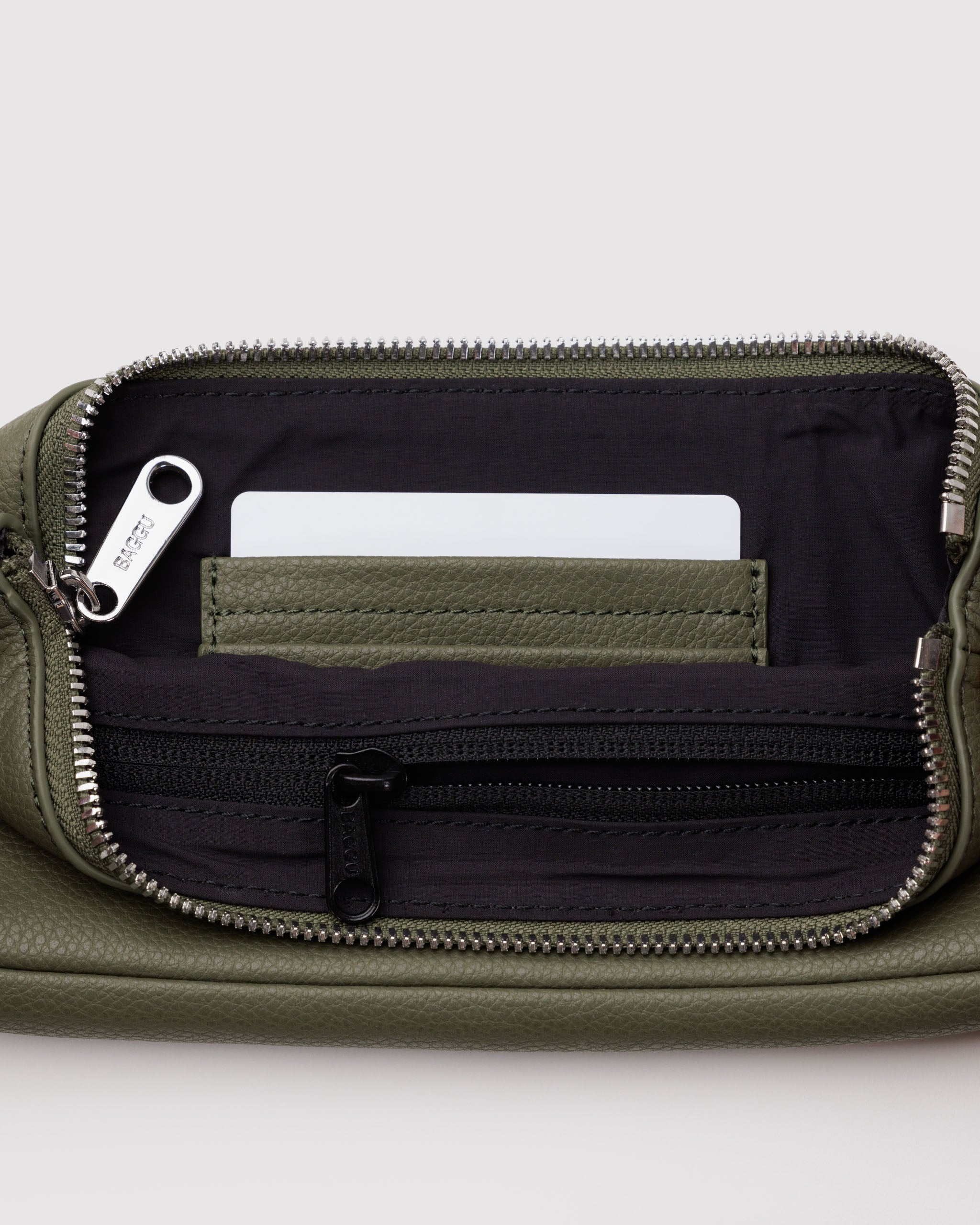 Green leather bag with metal zip open showing inside black lining with zip pouch and leather card slots.