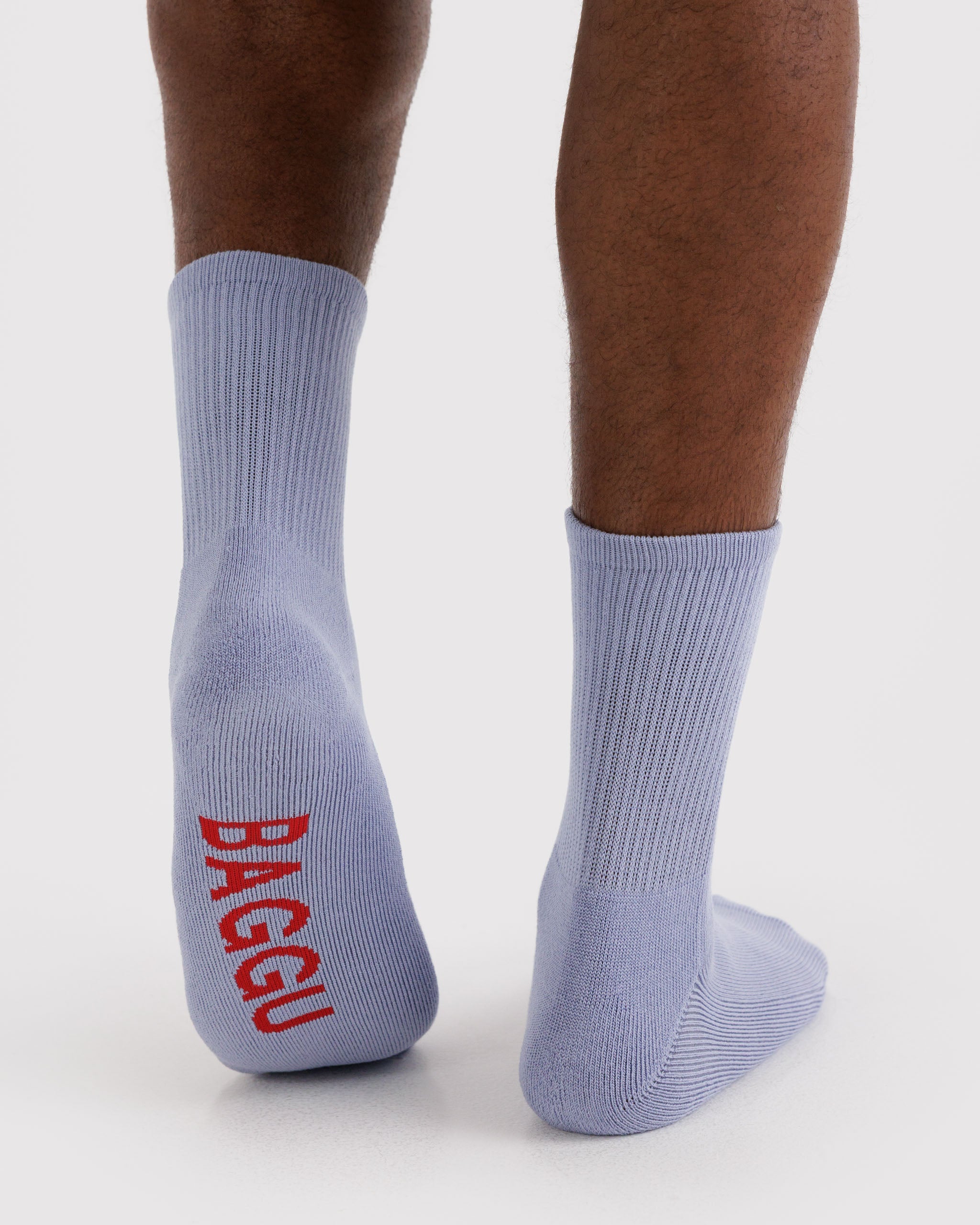 Light blue ribbed socks with red 'BAGGU' logo worn by a person.