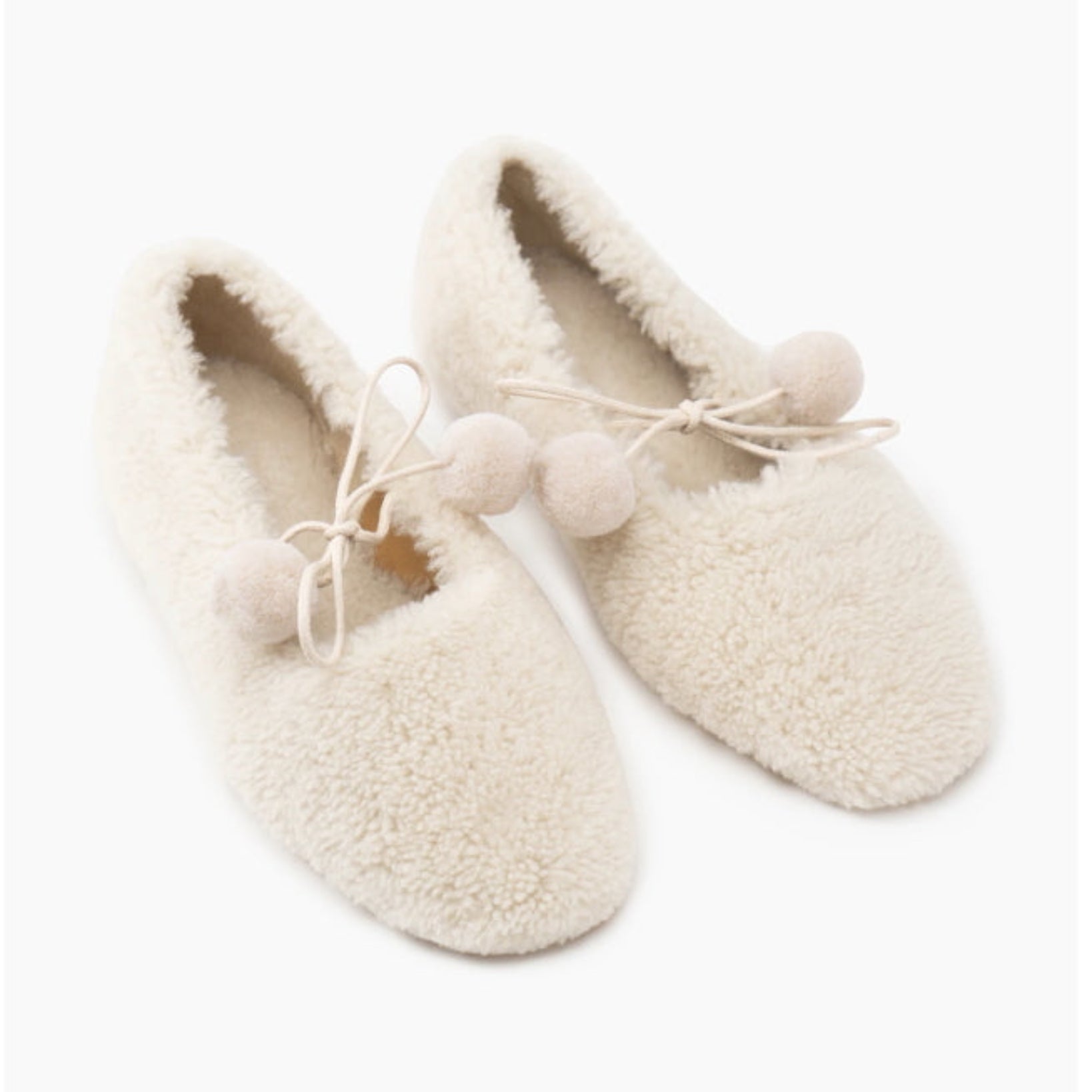 Pair of cream-coloured sheepskin slippers with pom-pom ties